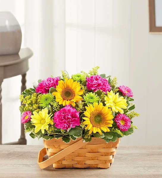 Basket of yellow sunflowers, pink carnations, and daisies