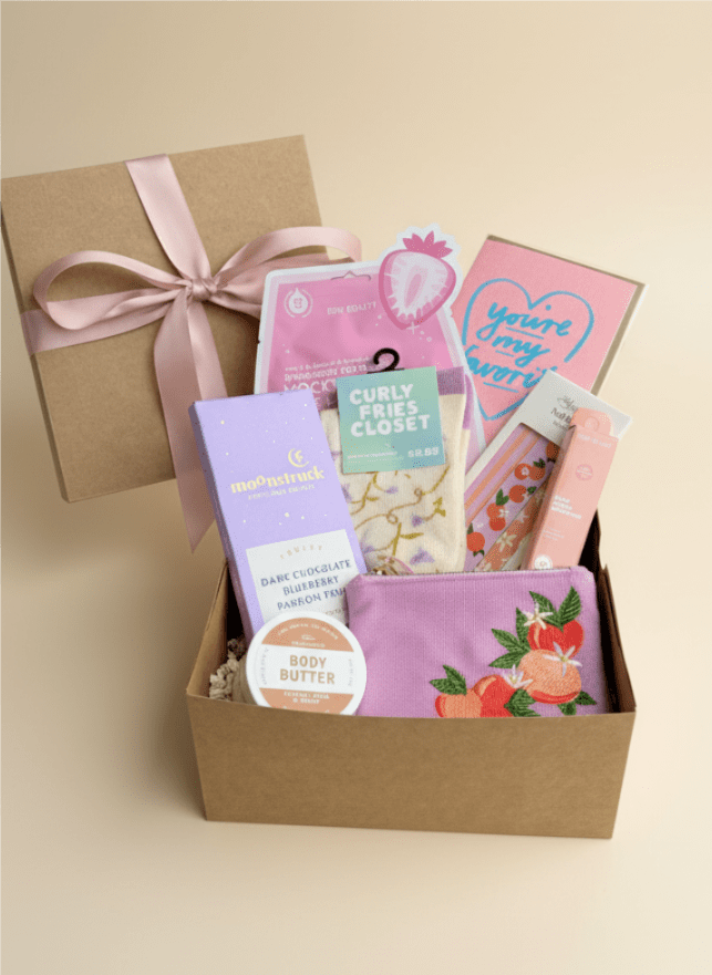 Gift box with assorted beauty items and a pink ribbon