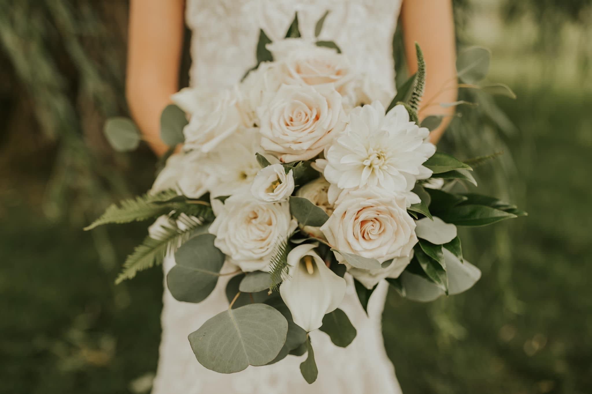 Bride holding a white bouquet of roses, dahlias, and calla lilies