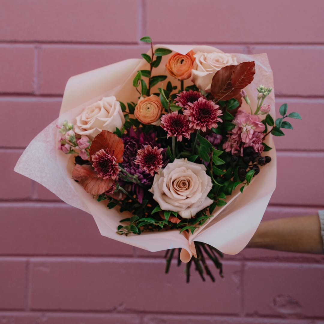 Bouquet of pale roses and pink-purple flowers wrapped in blush paper