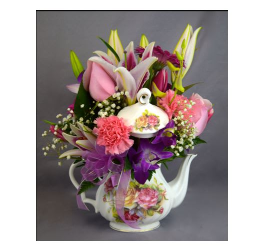 Bouquet of pink and purple flowers in a floral teapot vase
