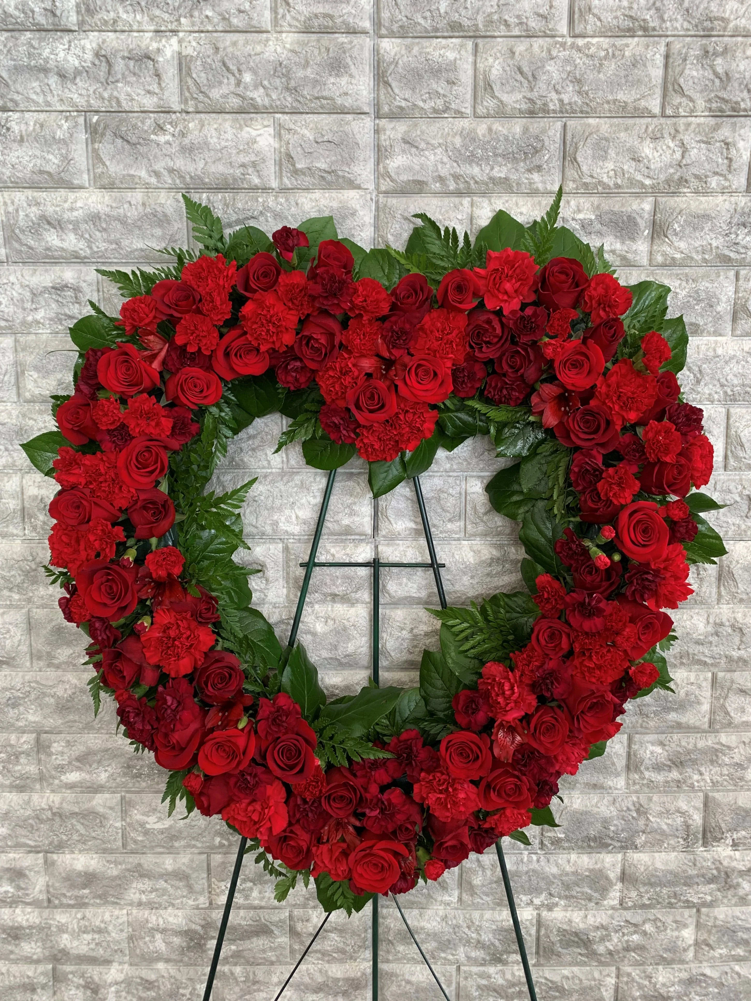 Heart-shaped red floral wreath on a stand