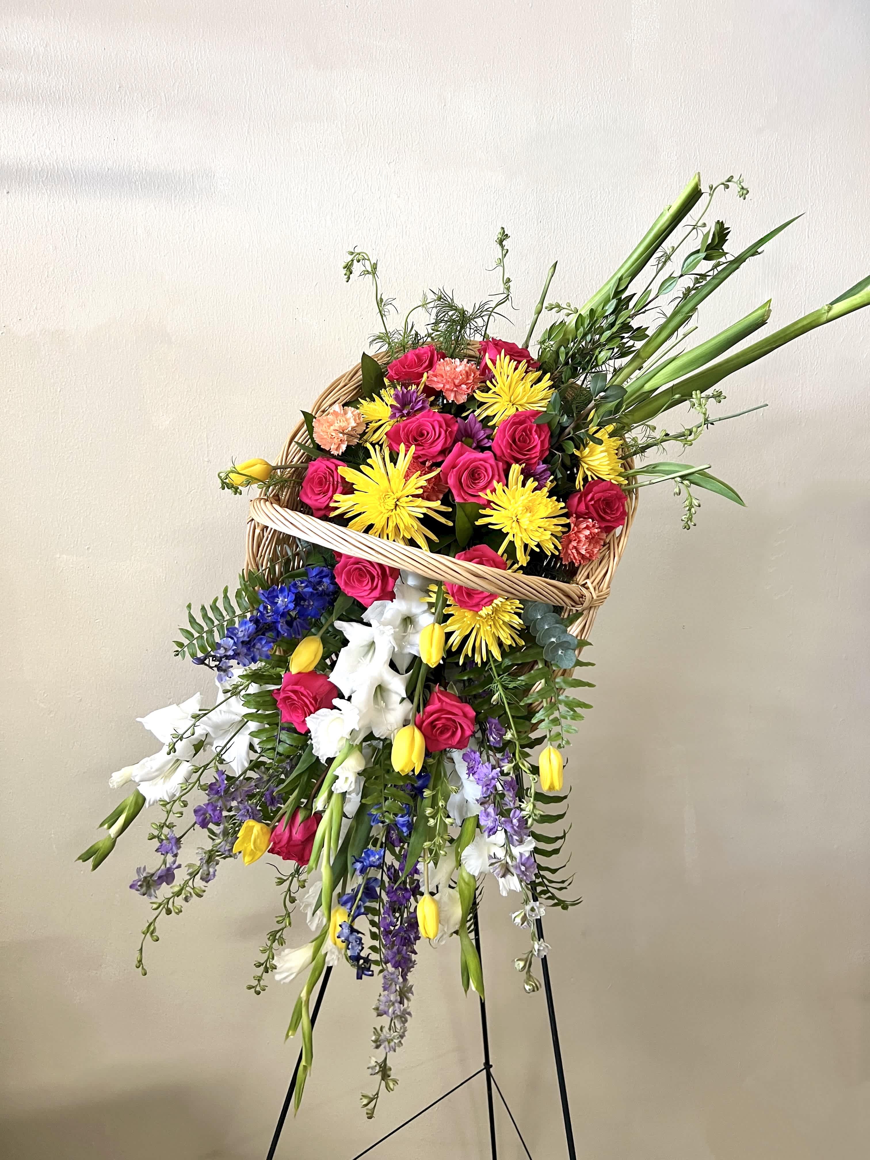 Large mixed flower basket on a stand with bright pink, yellow, white, and purple blooms