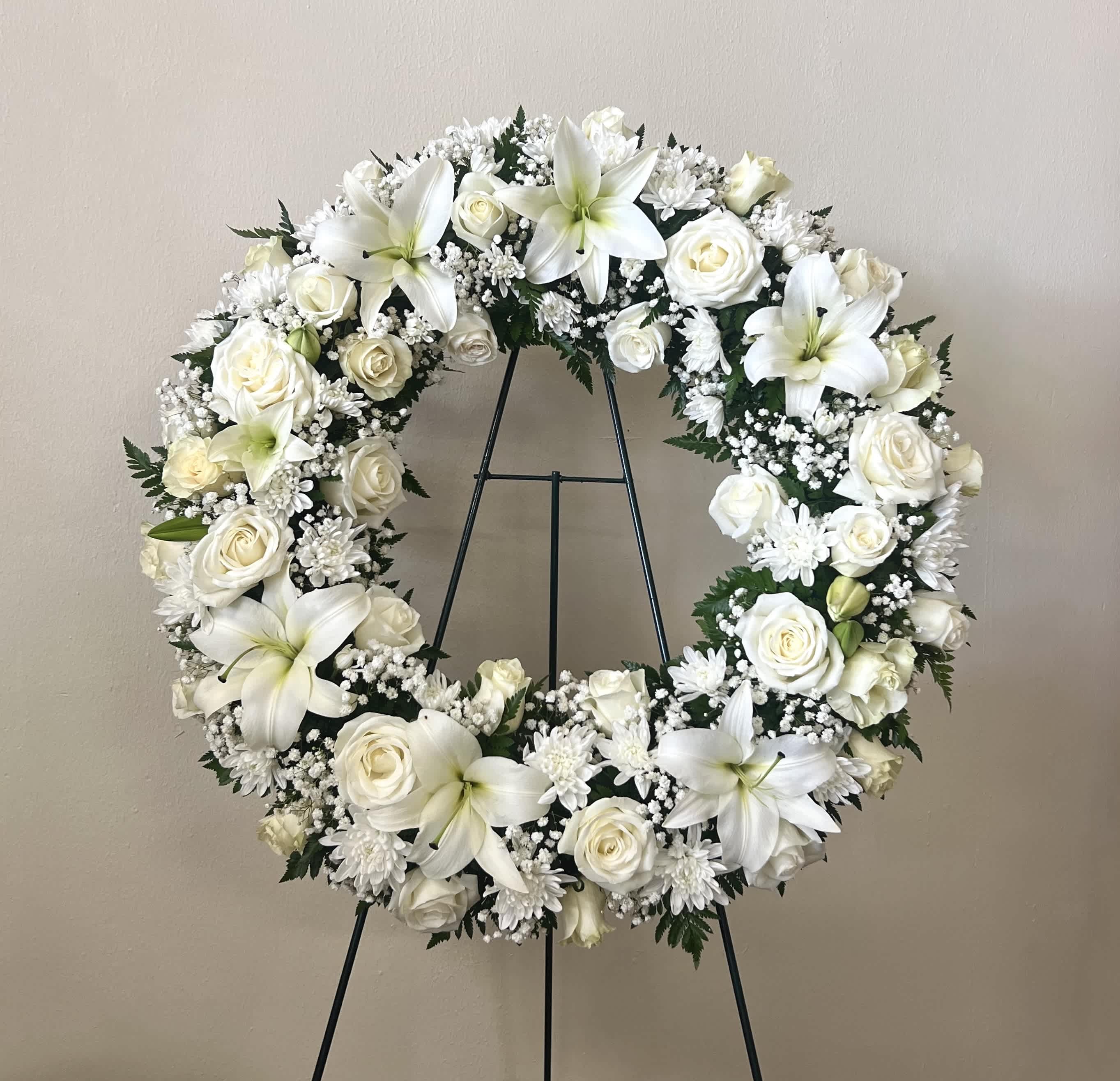 White floral wreath on a black stand
