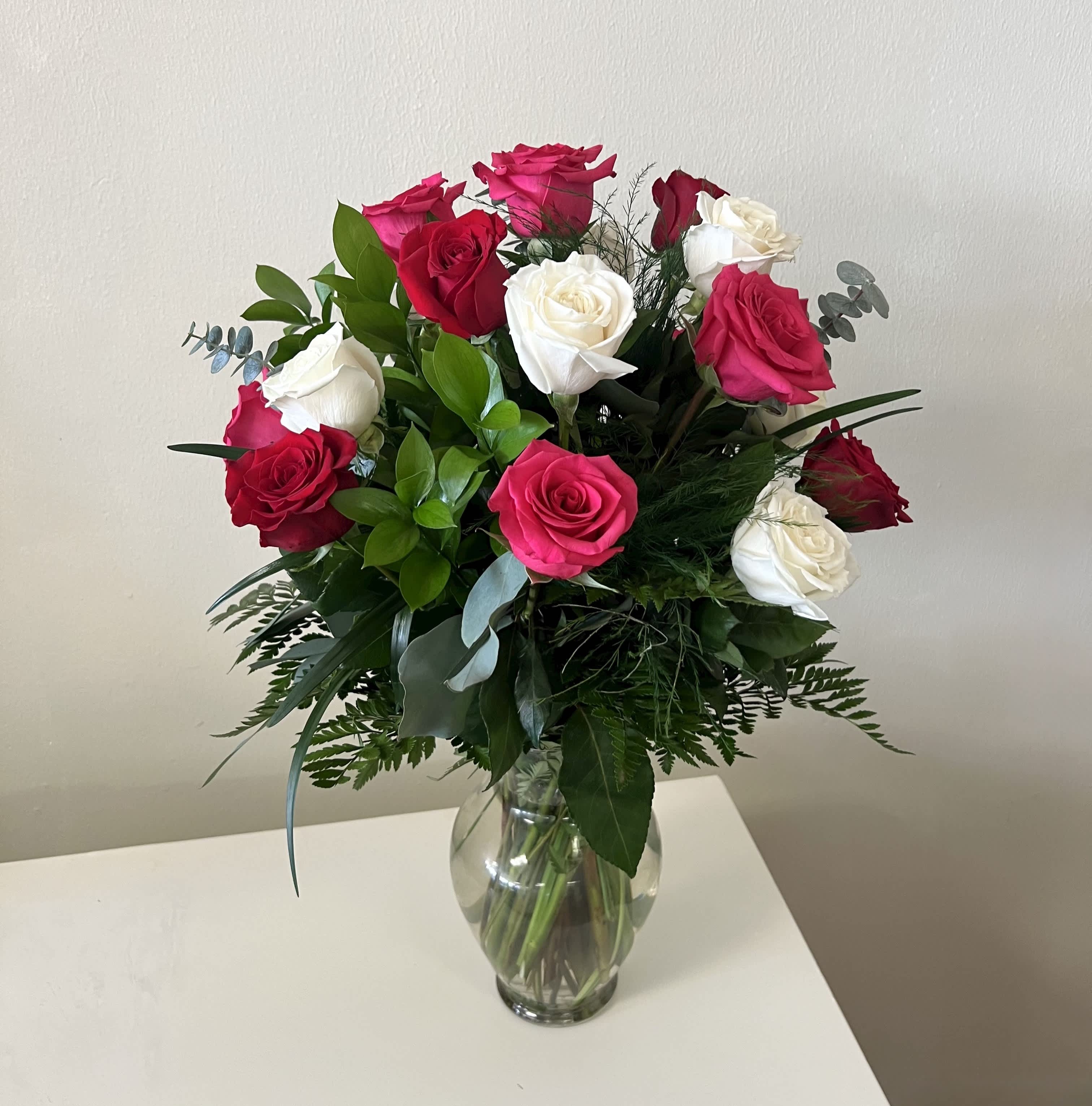 Bouquet of red, pink, and white roses in a clear glass vase