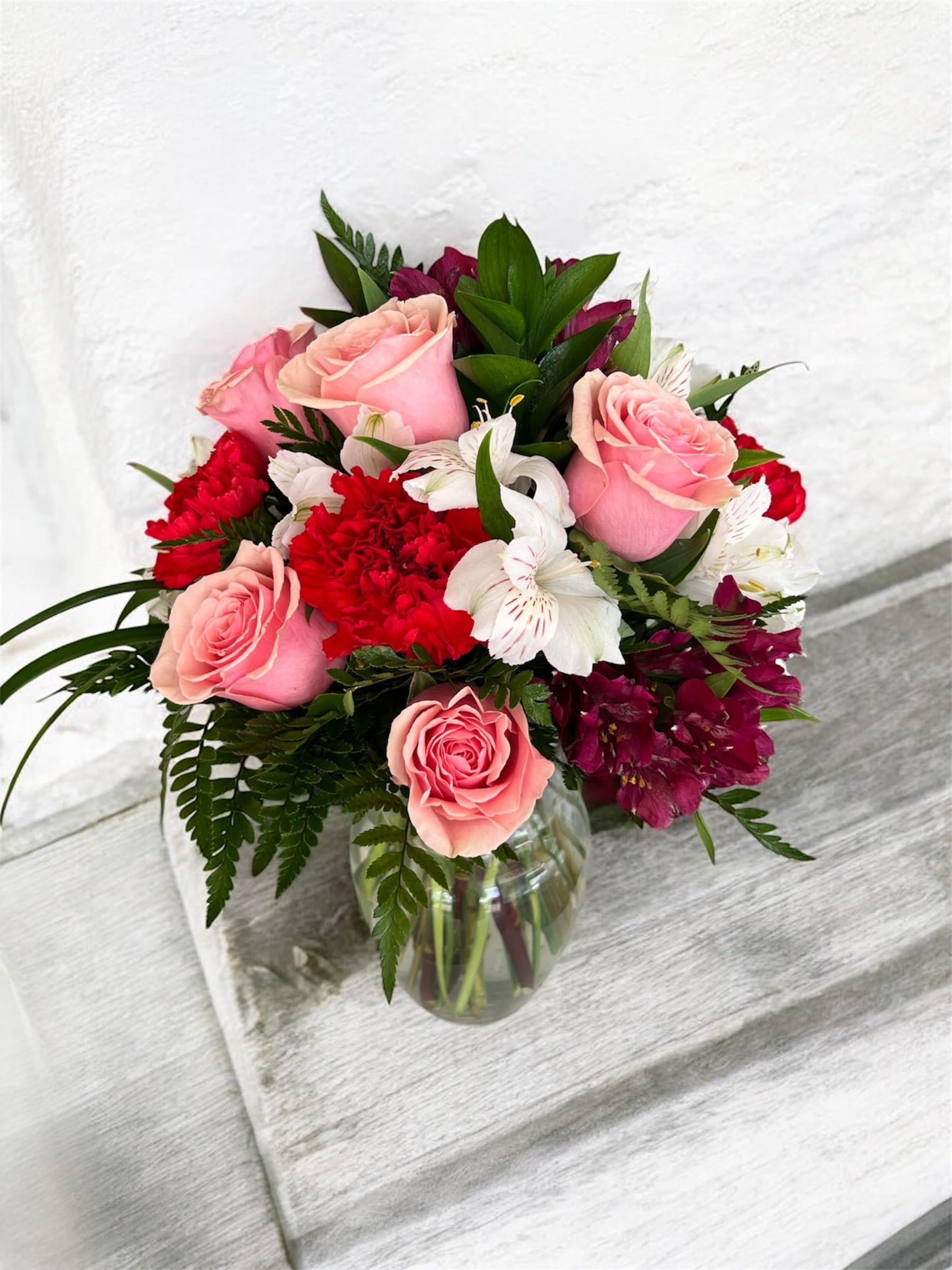 Pink roses and red flowers arranged in a glass vase