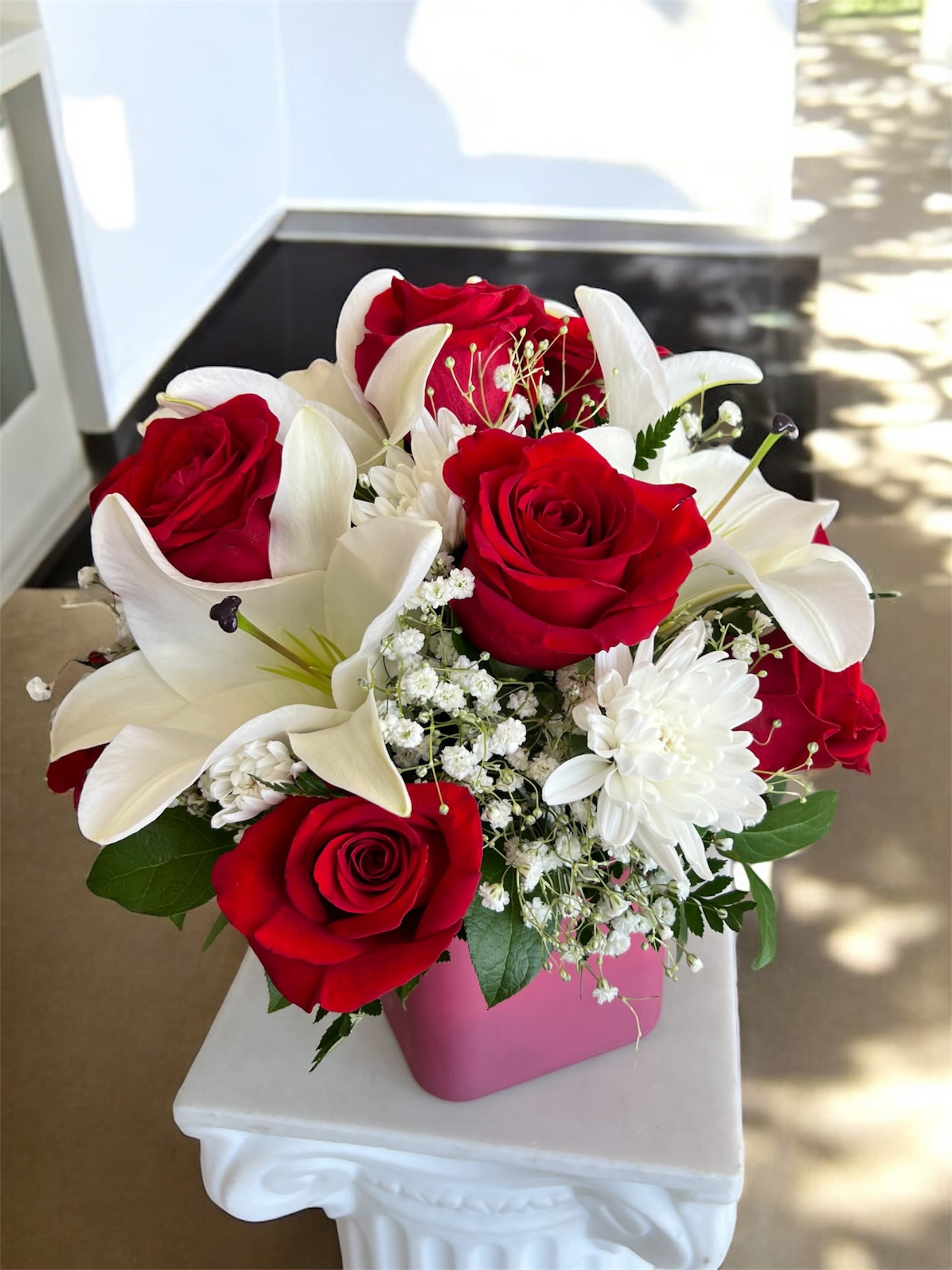 Red roses and white lilies in a pink vase
