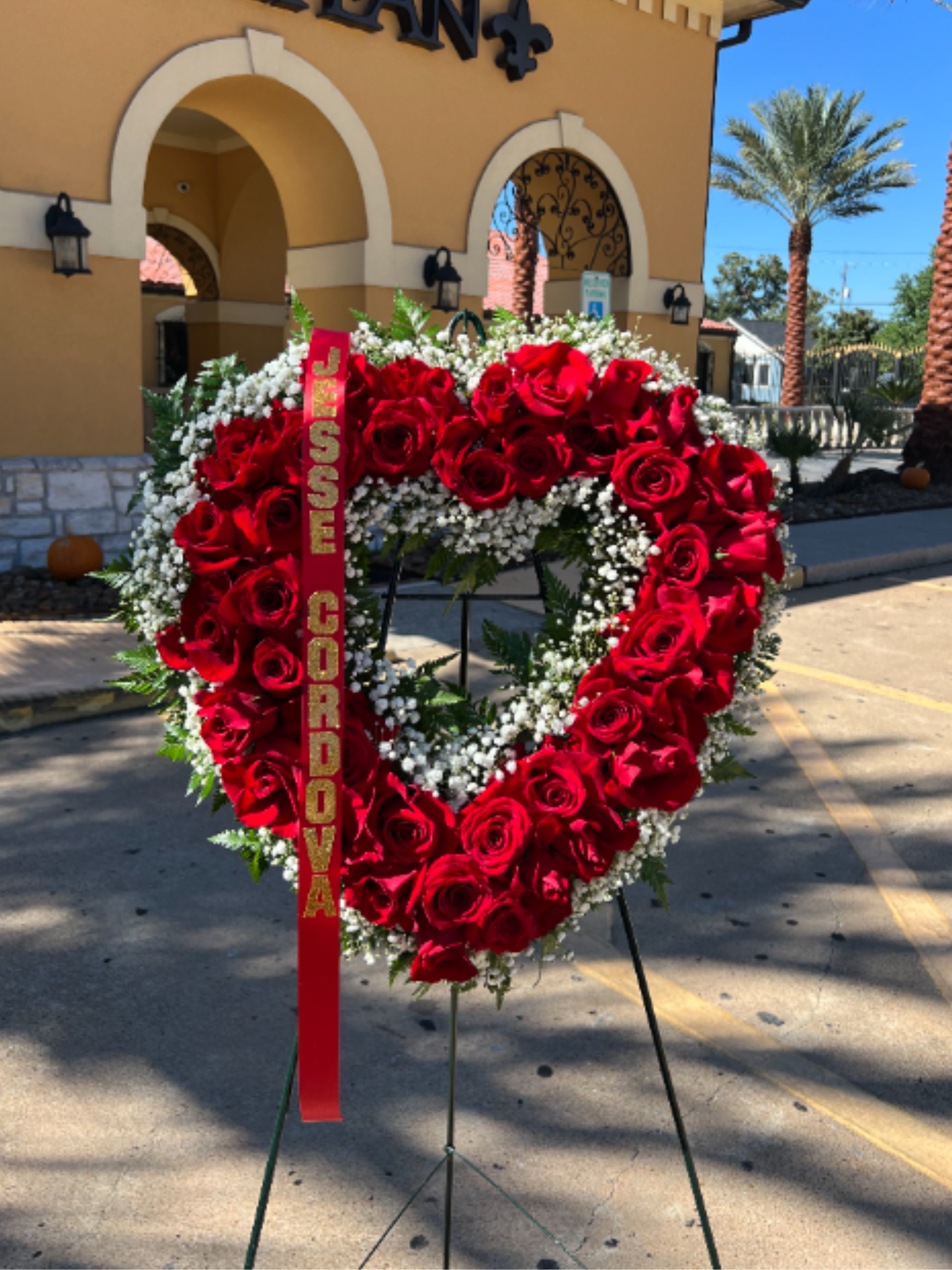 Loved and Remembered Always  - An 18" heart-shaped standing wreath made with premium red roses and accented with delicate baby’s breath. Elegant, classic, and heartfelt—perfect for expressing love and remembrance. (Ribbon included)  Arreglo en forma de corazón 18" elaborado con rosas rojas premium y delicado nube (baby’s breath). Un diseño elegante, clásico y lleno de sentimiento para expresar amor y recuerdo. (Liston inluido)  Ribbon/Liston  Please include the ribbon wording in special instructions tab/Por favor inlcuya el texto del liston en la caja de instrucciones especiales. 
