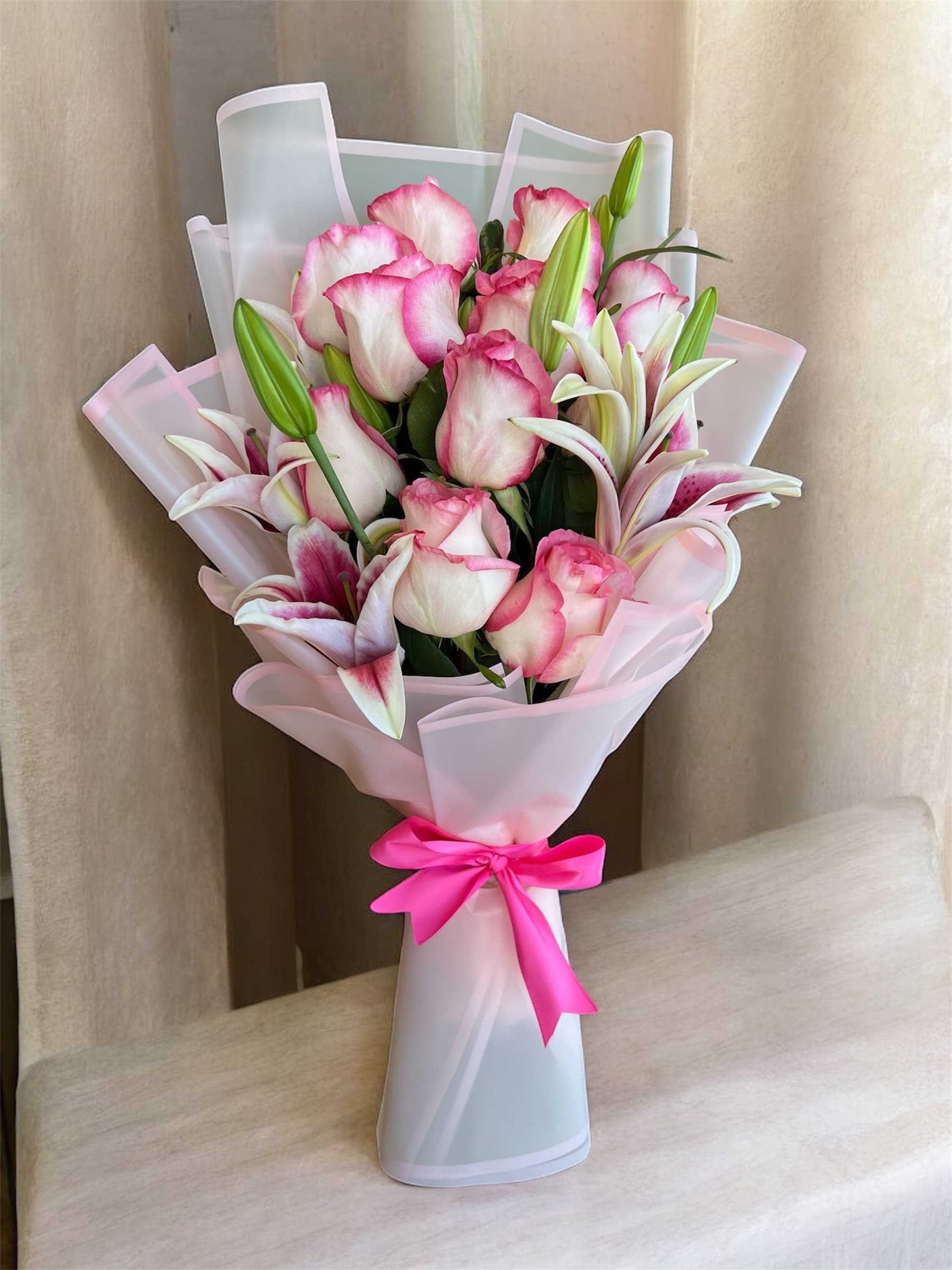 Pink and white rose bouquet with lilies wrapped in pale pink paper