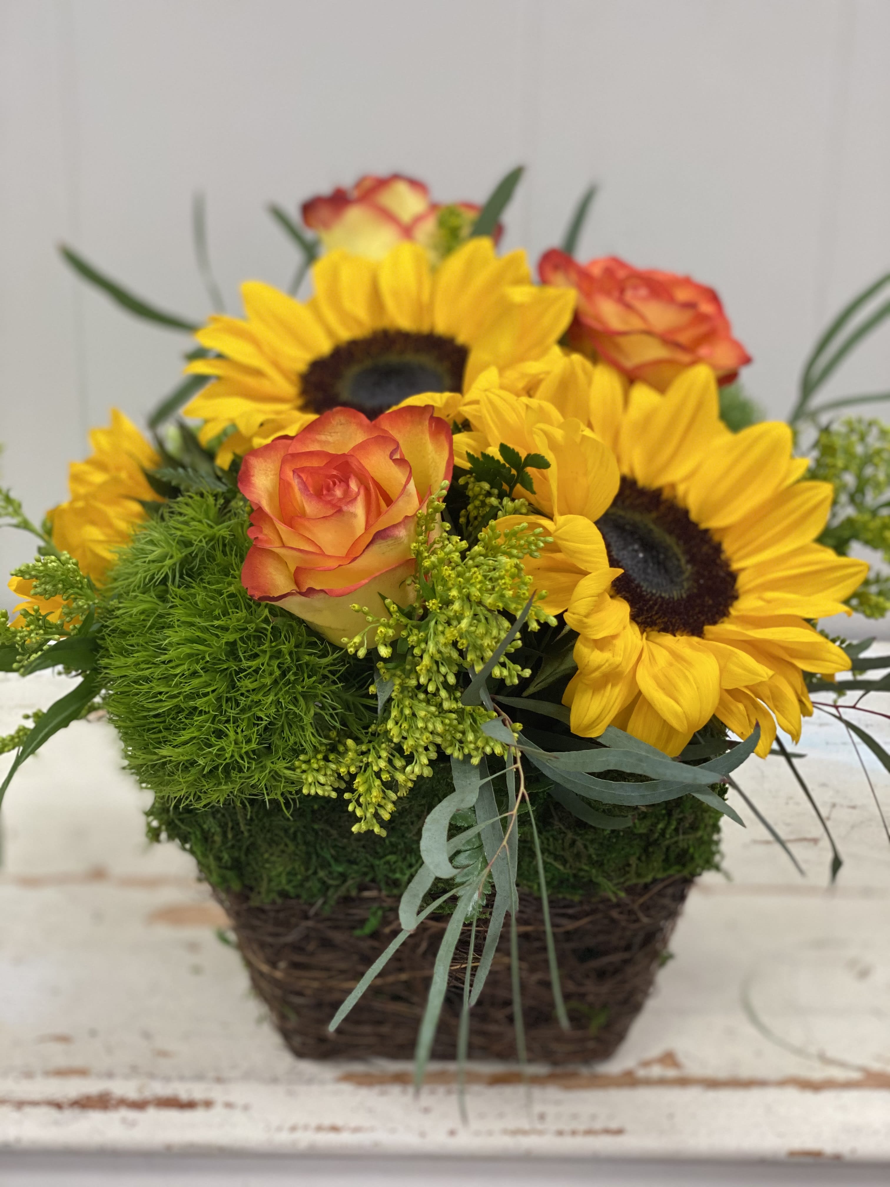 Sunflowers and orange roses in a wicker basket
