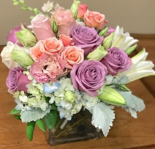 Bouquet of pink and purple roses with white lilies in a glass vase