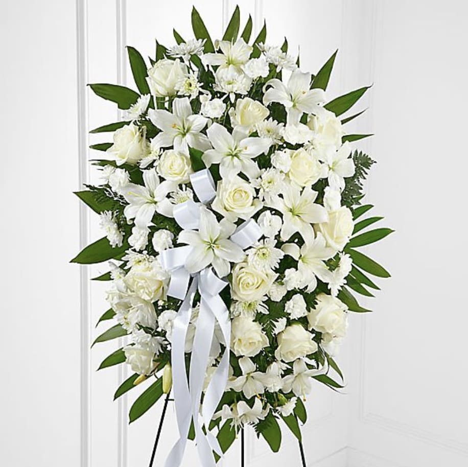 White funeral spray with roses and lilies on a stand