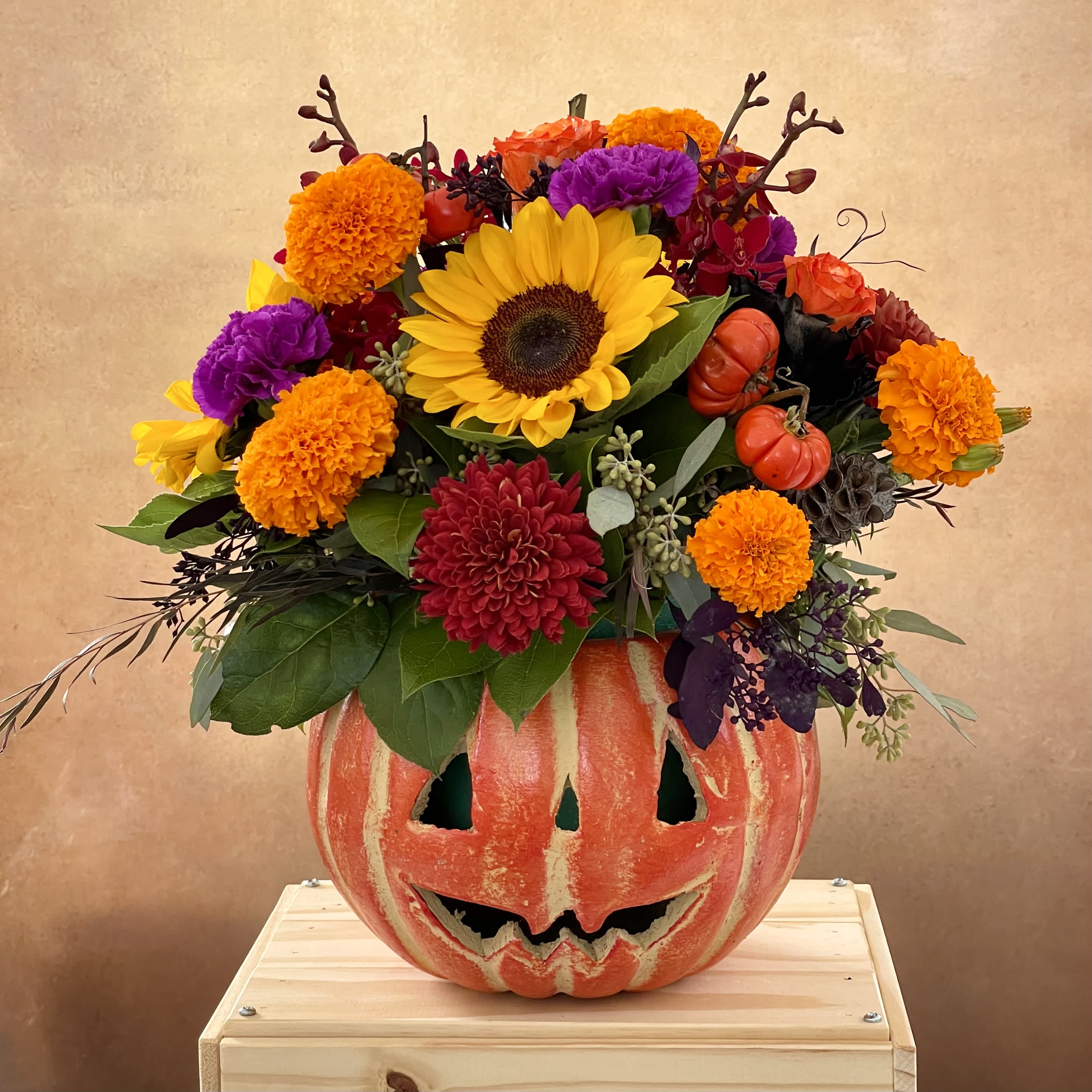 Sunflower and mixed fall flowers arranged in a carved pumpkin container