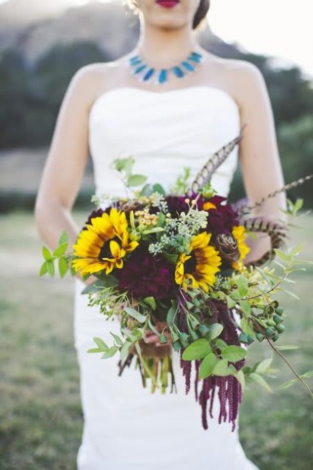 Bride holding a bouquet with sunflowers and trailing greenery