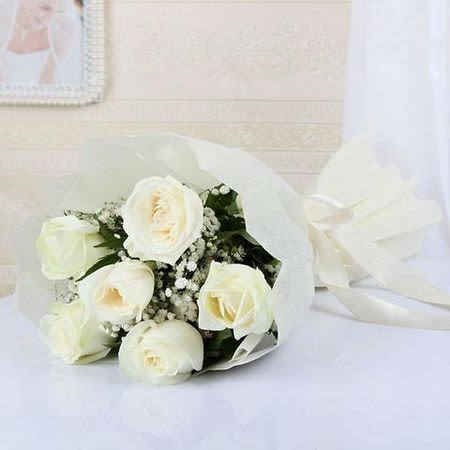 White rose bouquet wrapped in white paper with a ribbon