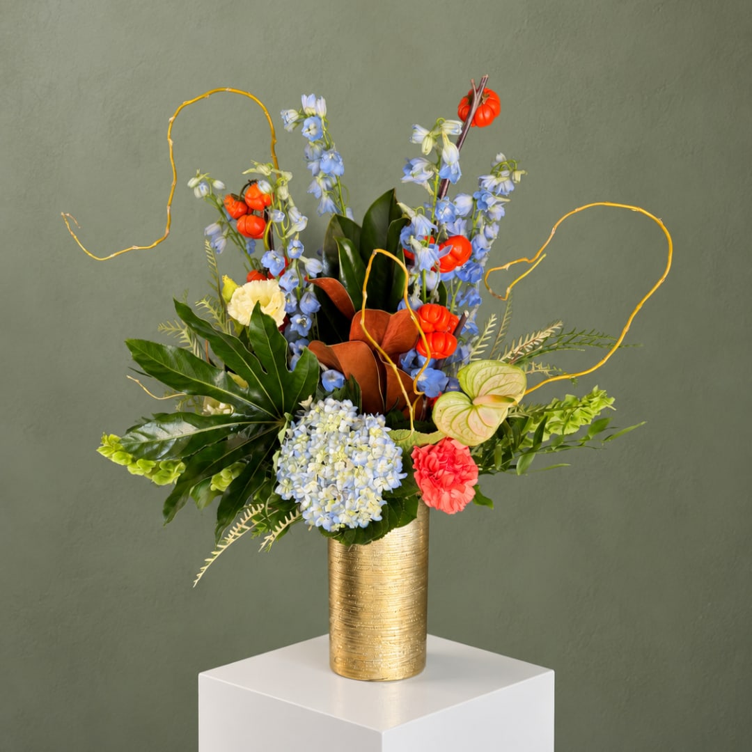 Colorful floral arrangement in a gold vase with blue and orange blooms