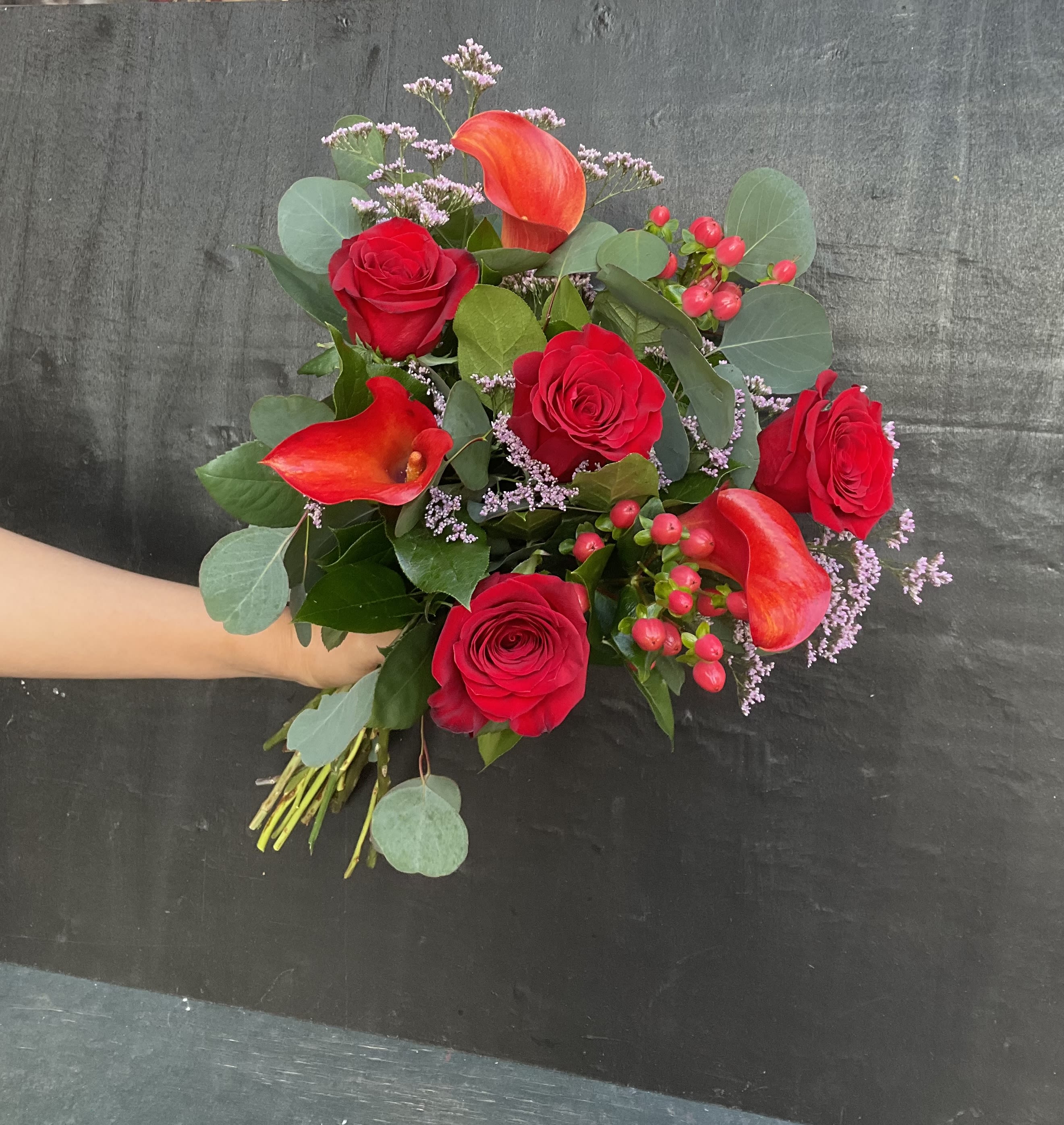 Bouquet of red roses and orange calla lilies with greenery
