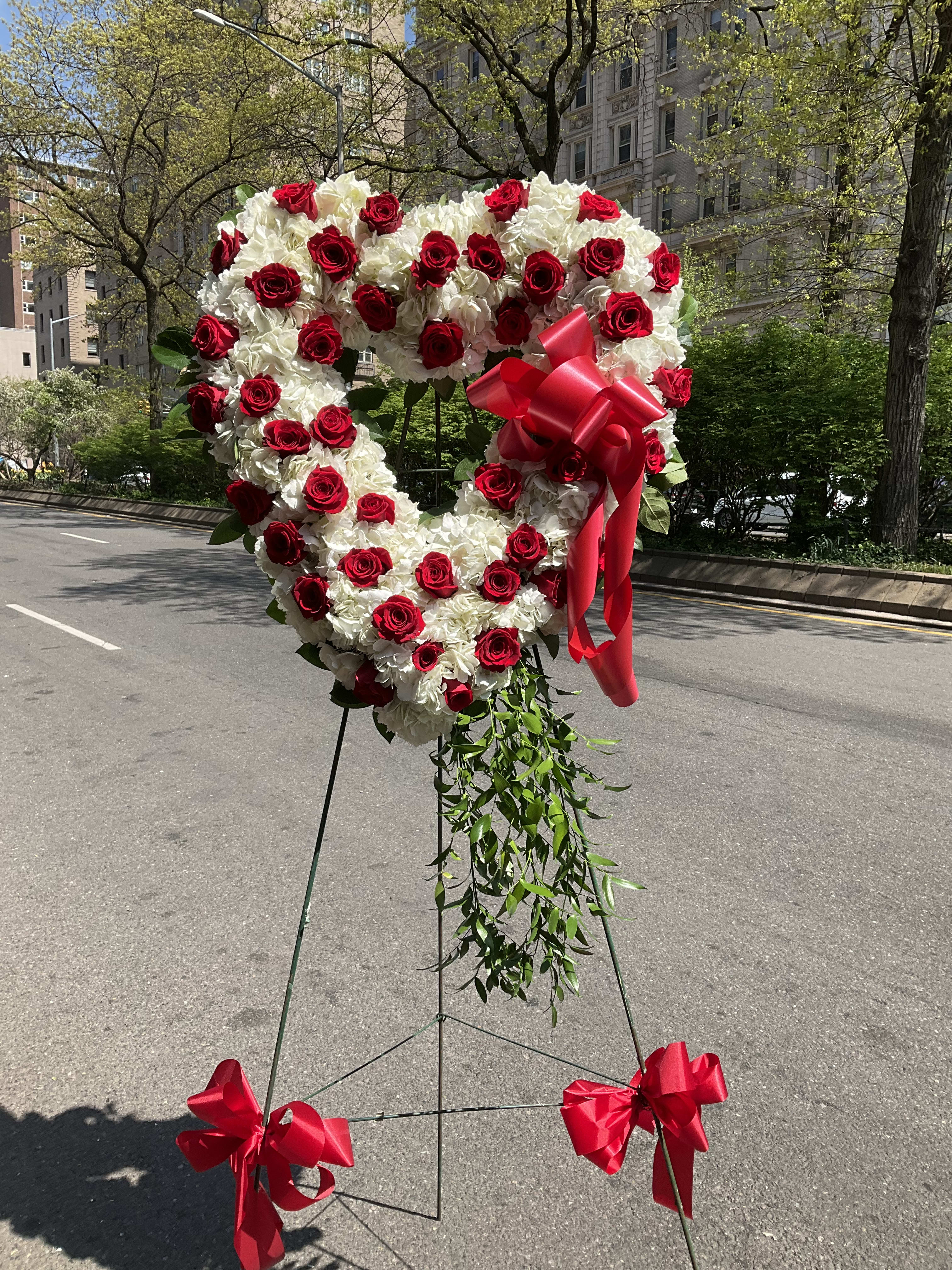 Heart-shaped red and white floral standing arrangement with ribbon
