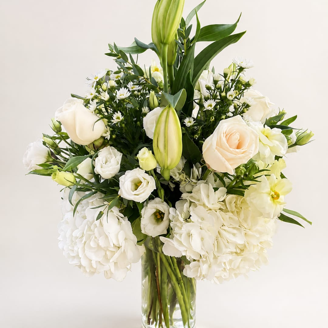 White roses and lilies arranged in a clear glass vase