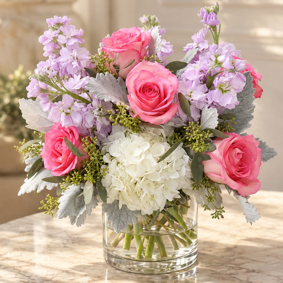Pink roses and lavender flowers arranged in a clear glass vase