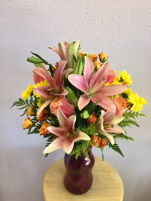 Lilies Of Love by Forever Flowers - A full and colorful arrangement for any occasion. Contains pink lilies, peach roses, orange spray roses, and other blooms. 