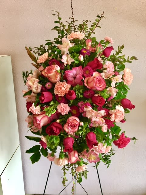 Standing floral spray with pink roses and carnations on a black easel