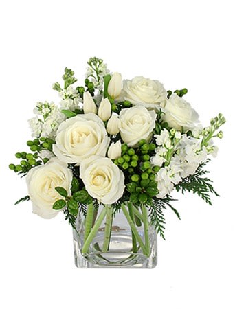 White roses and tulips arranged in a clear glass vase