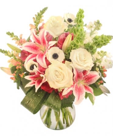 Bouquet of pink lilies, white roses, and white anemones in a glass vase