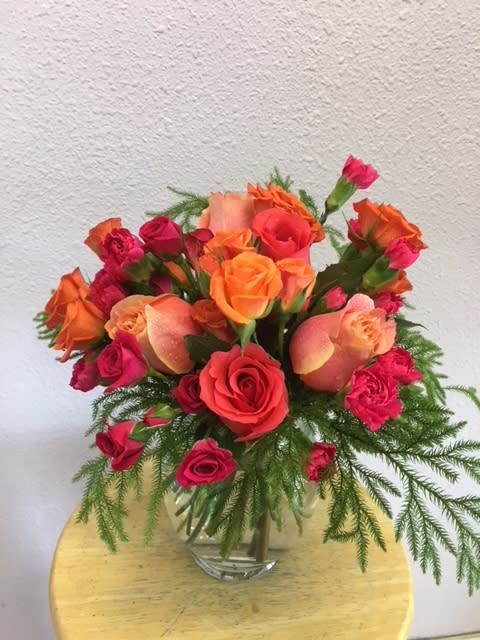 Bouquet of orange and pink roses in a clear glass vase