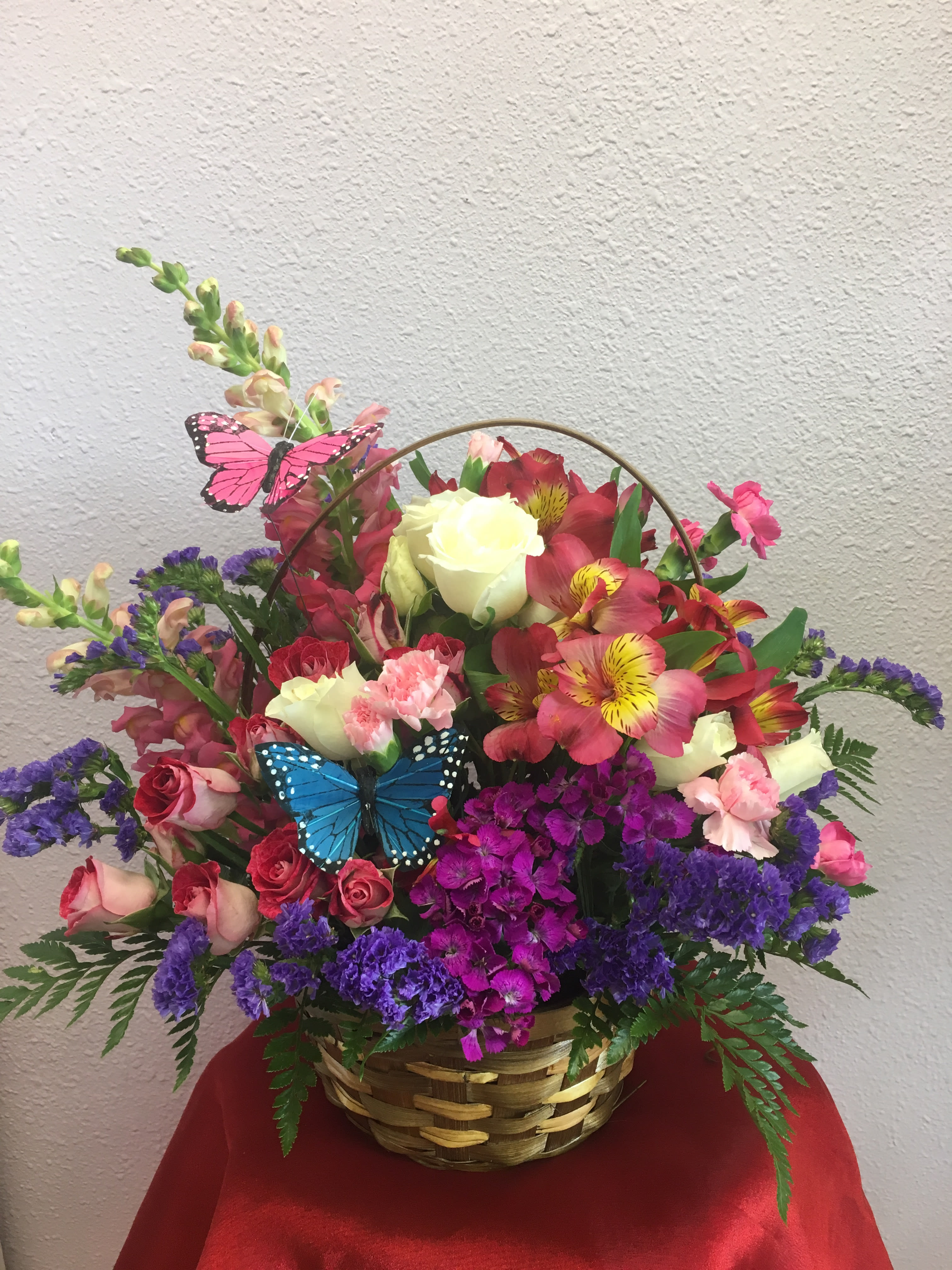 Fantasy Garden by Forever Flowers - A colorful arrangement with bright flowers and butterfly decorations.  Contains spray roses, snap dragons, carnations, and other blooms.