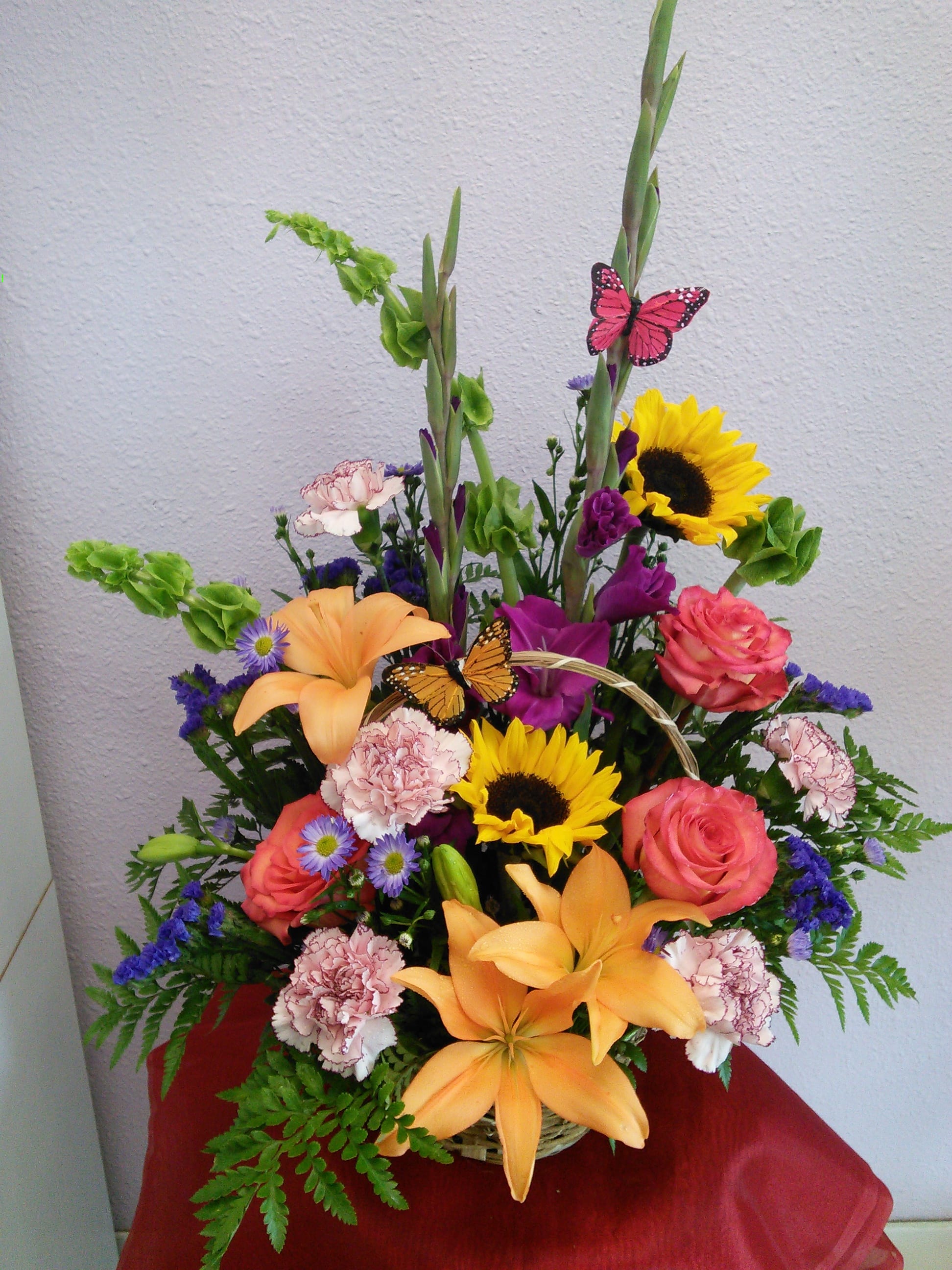 Basket Of Grace by Forever Flowers - Beautiful mix flower basket with sunflowers, gladiolas, orange roses, pink carnations and orange lilies. Perfect for any occasion. 