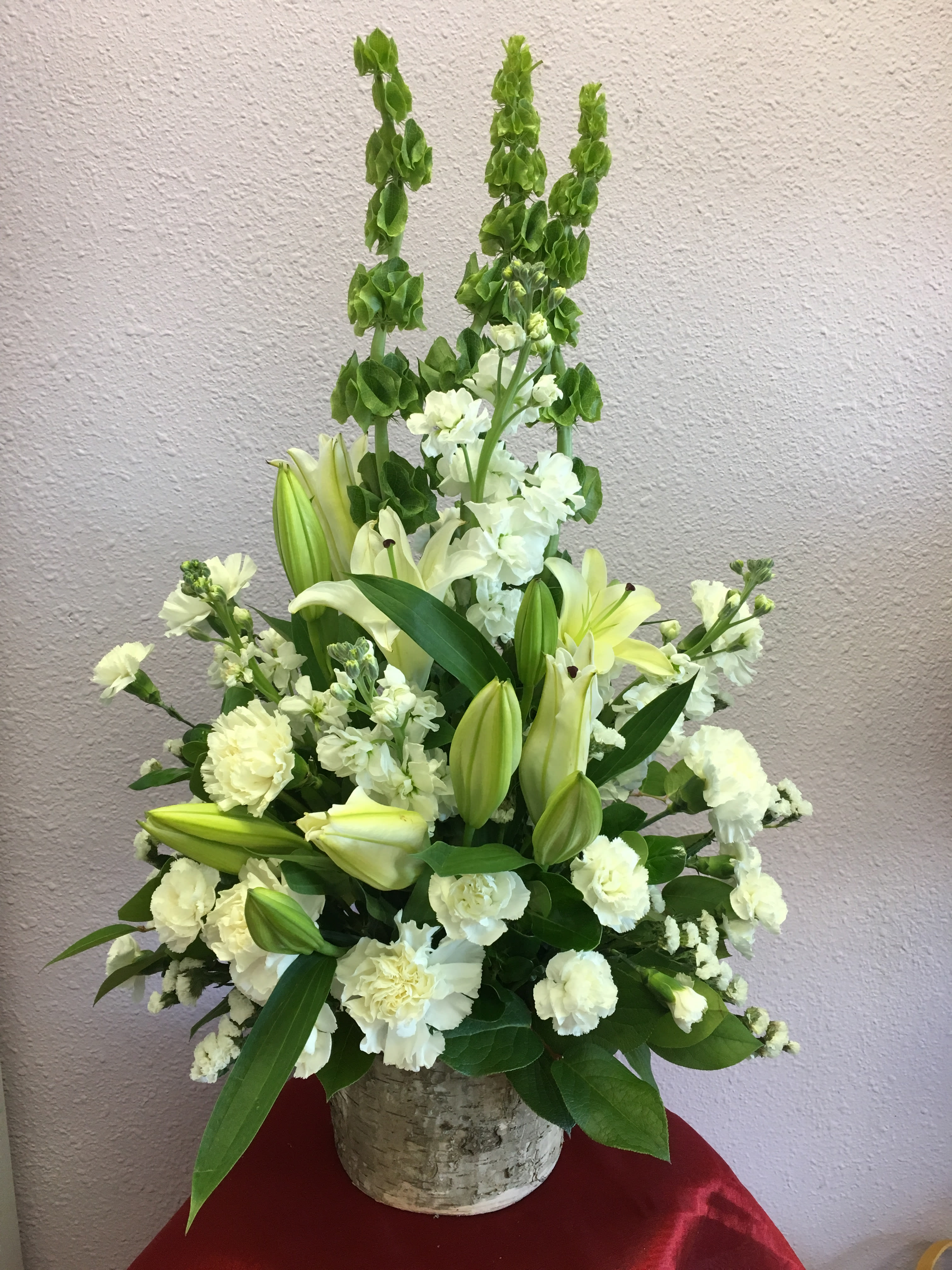 White floral arrangement with lilies and carnations in a textured vase
