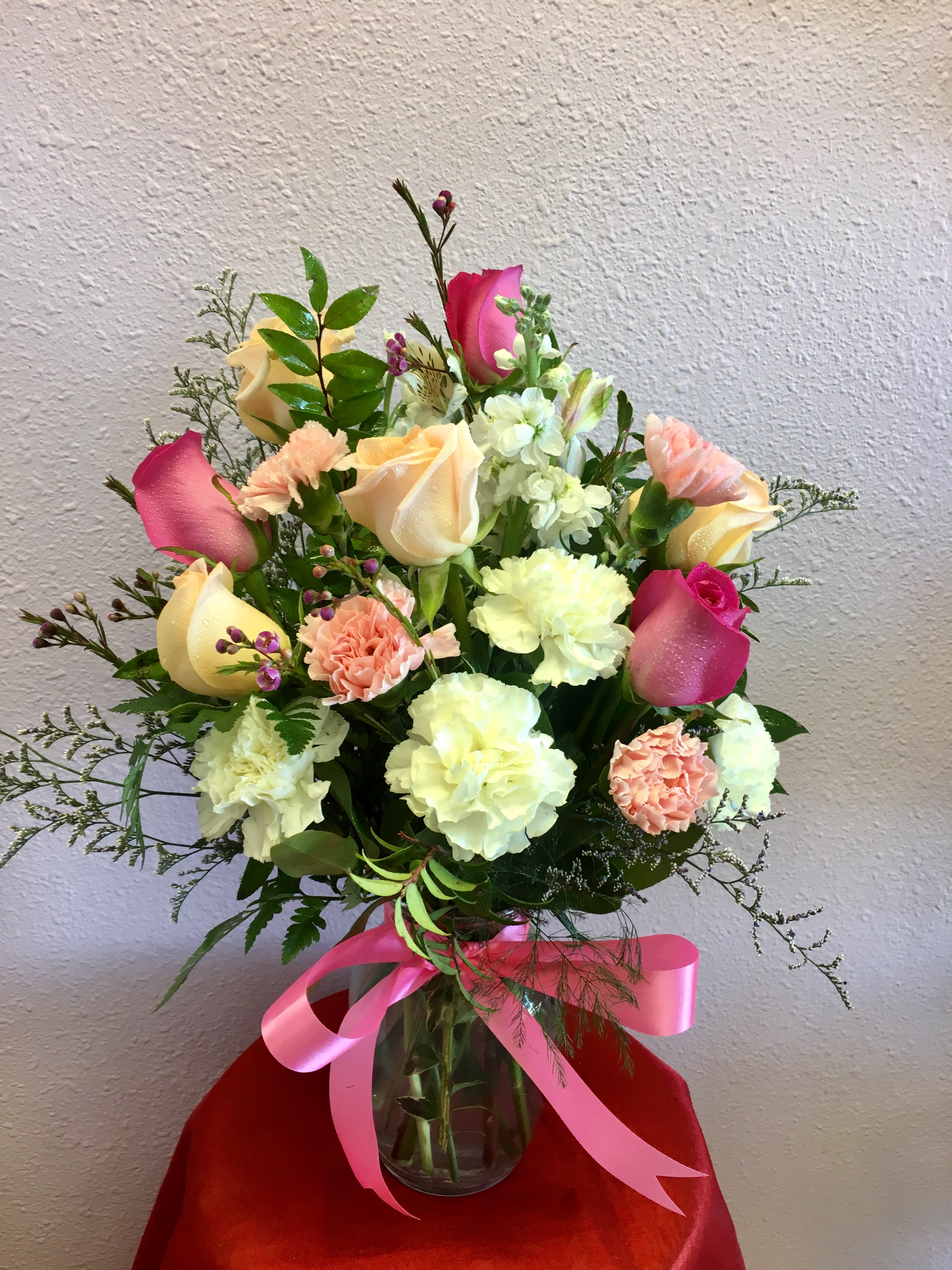 Bouquet of pink and cream roses with carnations in a glass vase