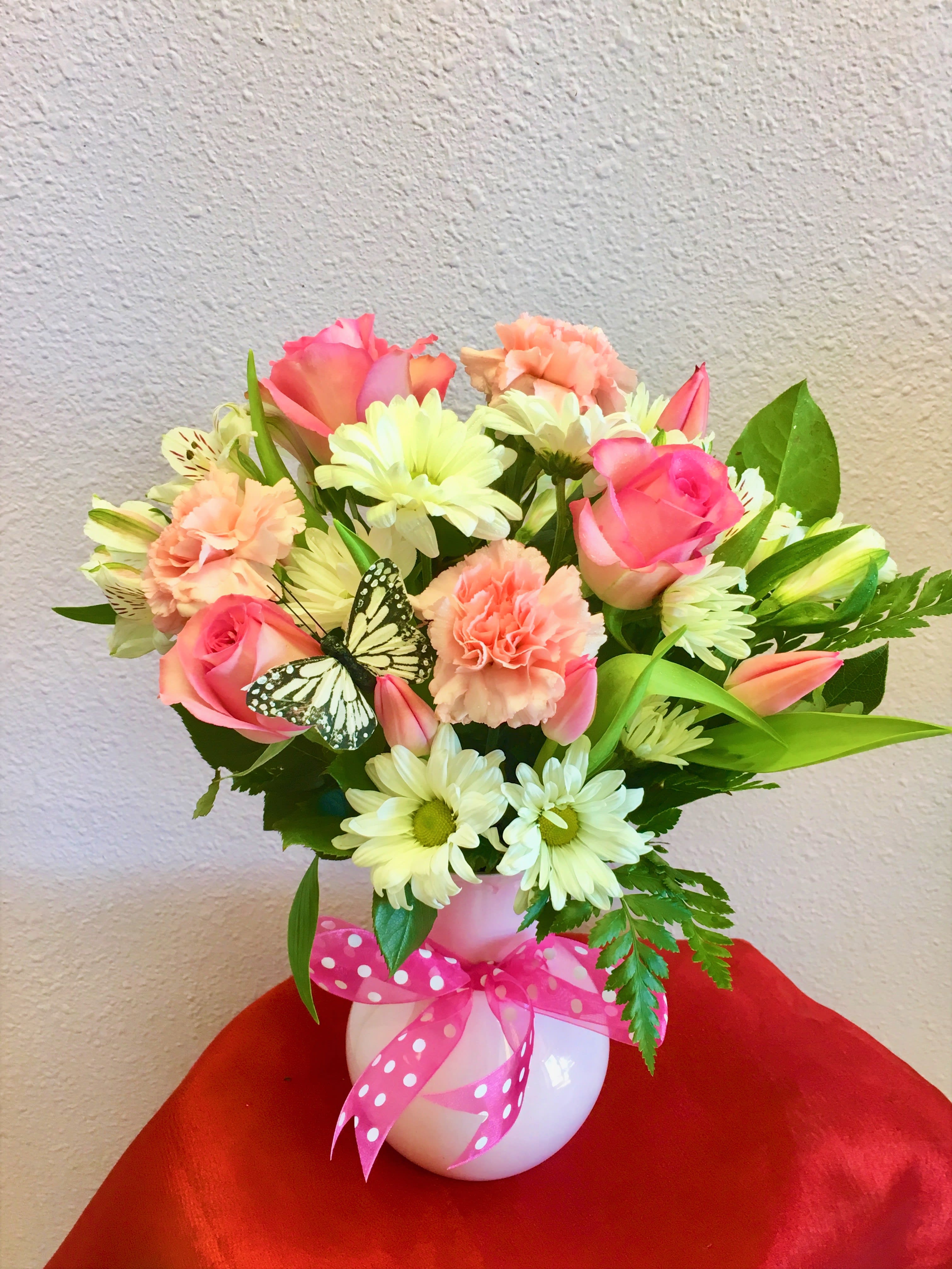 Pink and peach mixed bouquet in a white vase with a polka-dot ribbon