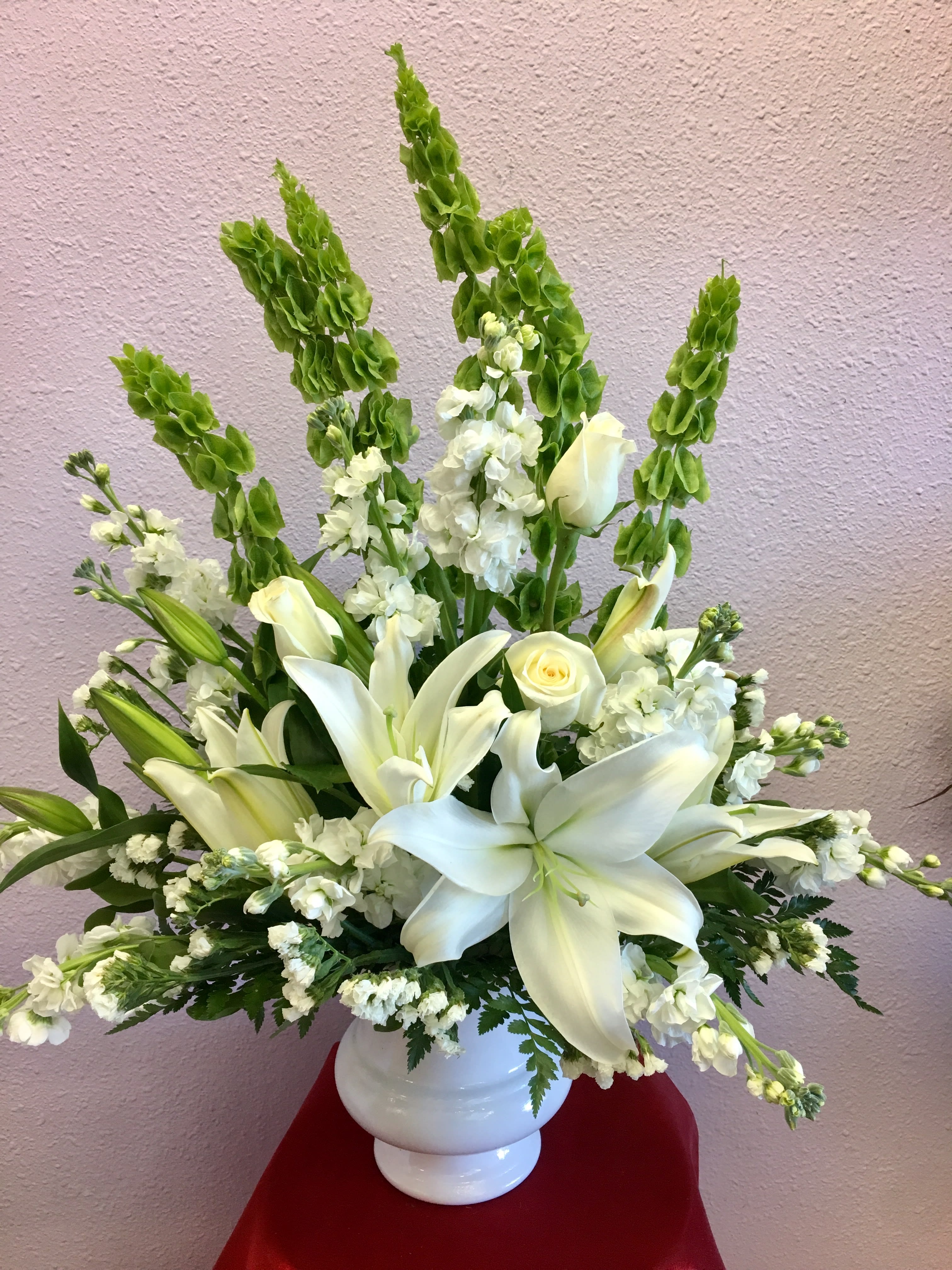 White lilies and roses in a white vase with tall green spikes