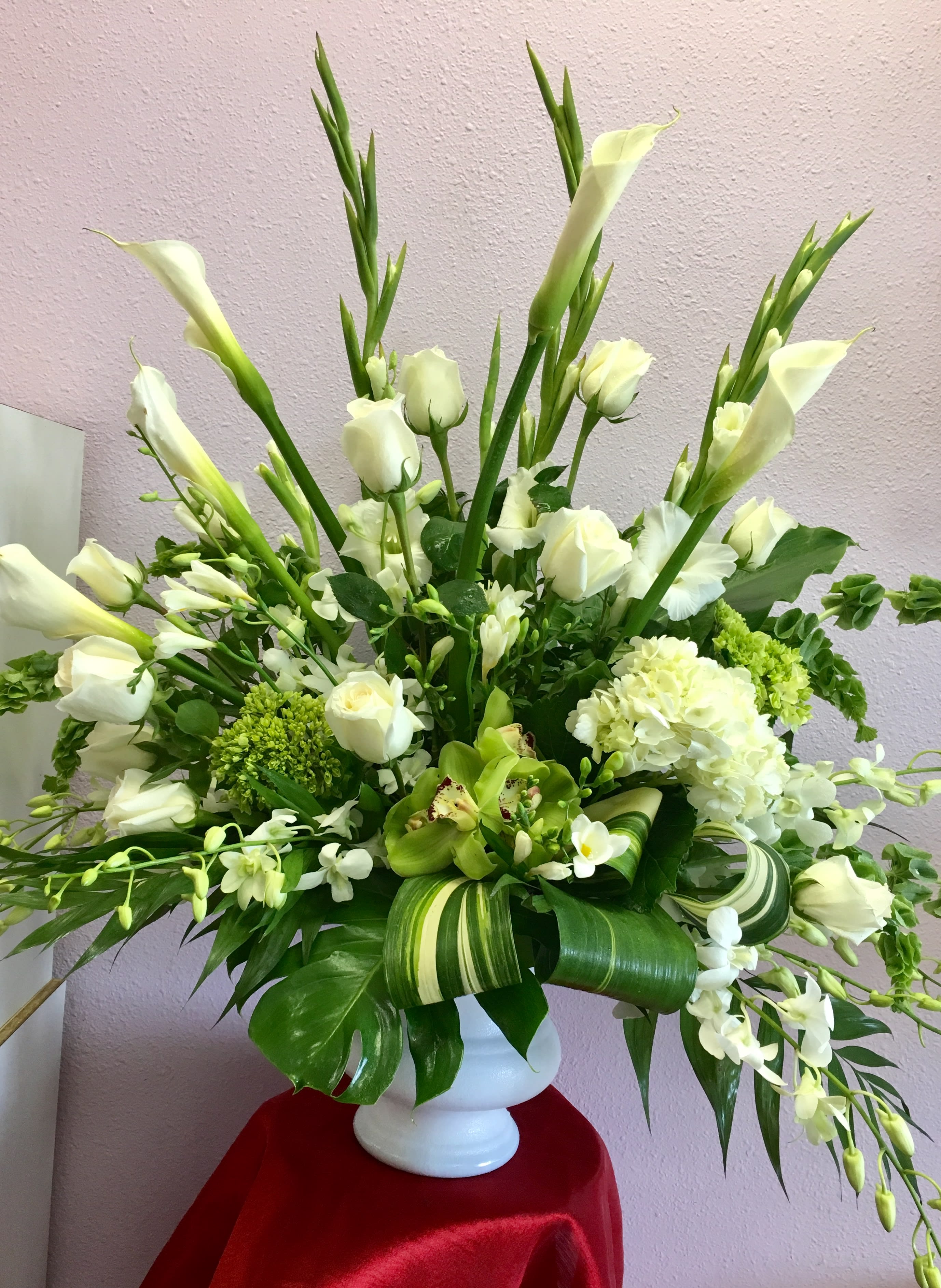 White floral arrangement in a white vase with tall calla lilies and roses