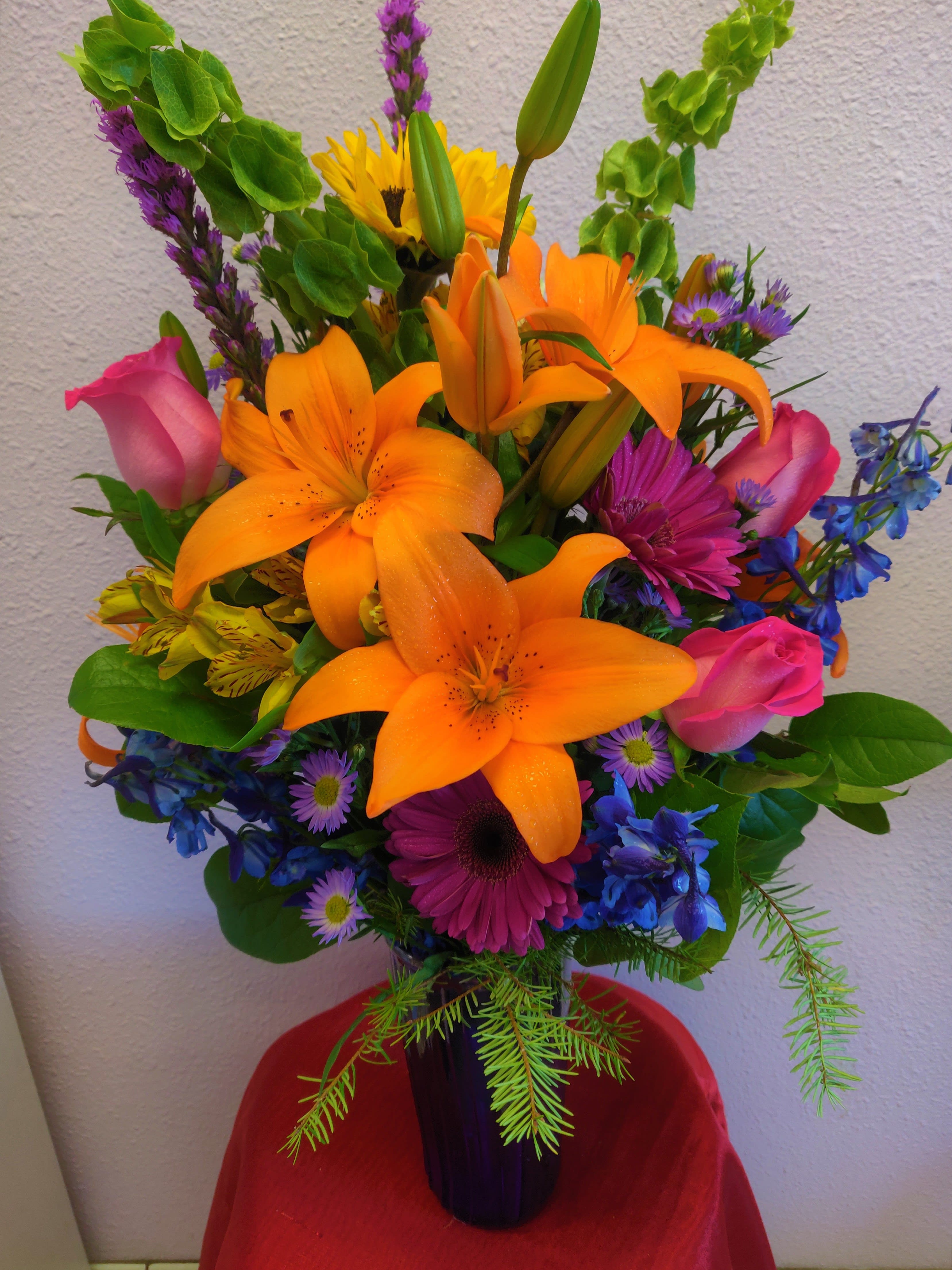 Colorful bouquet with orange lilies, pink roses, and purple flowers in a vase