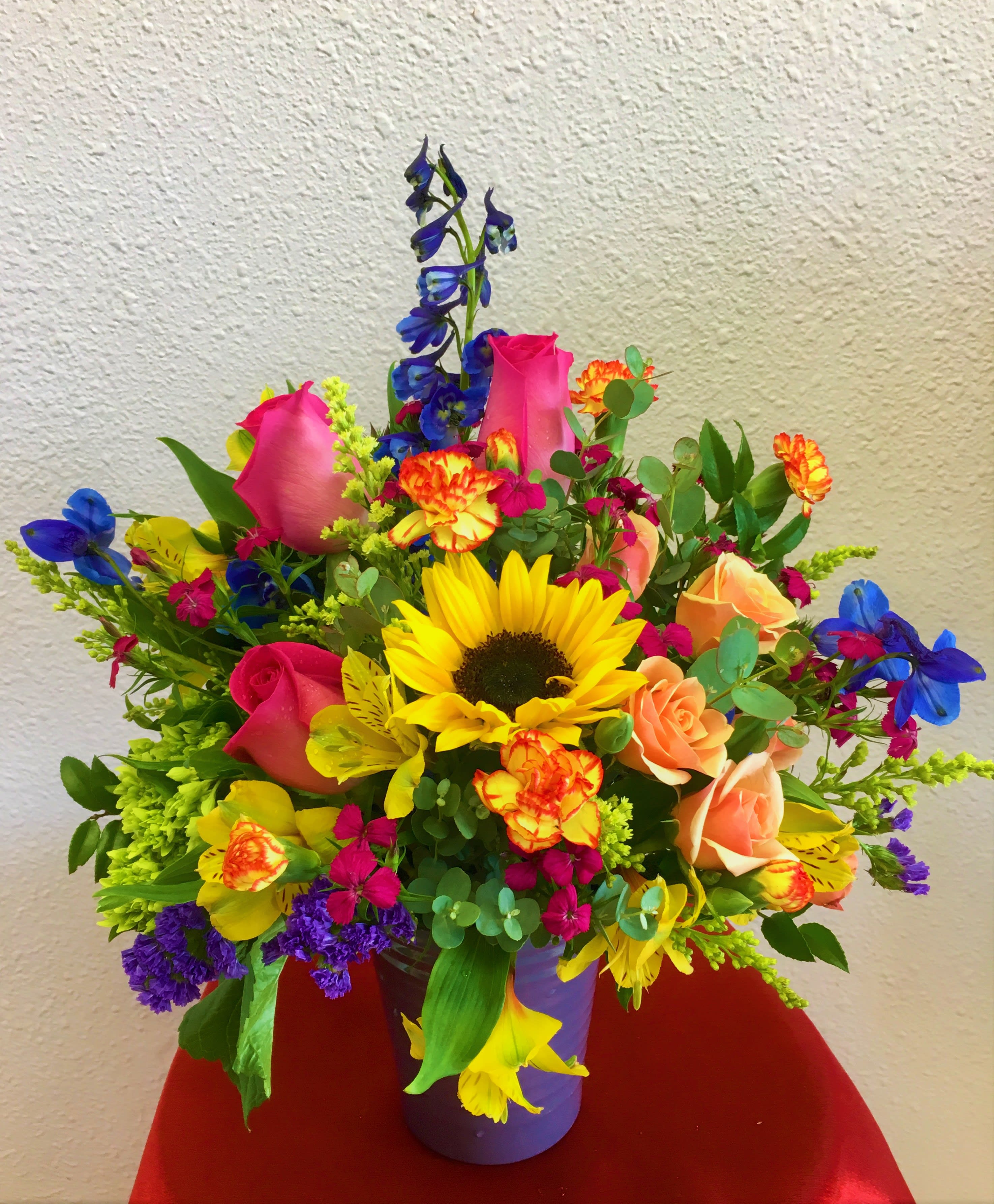 Colorful mixed bouquet in a purple vase with sunflowers and roses