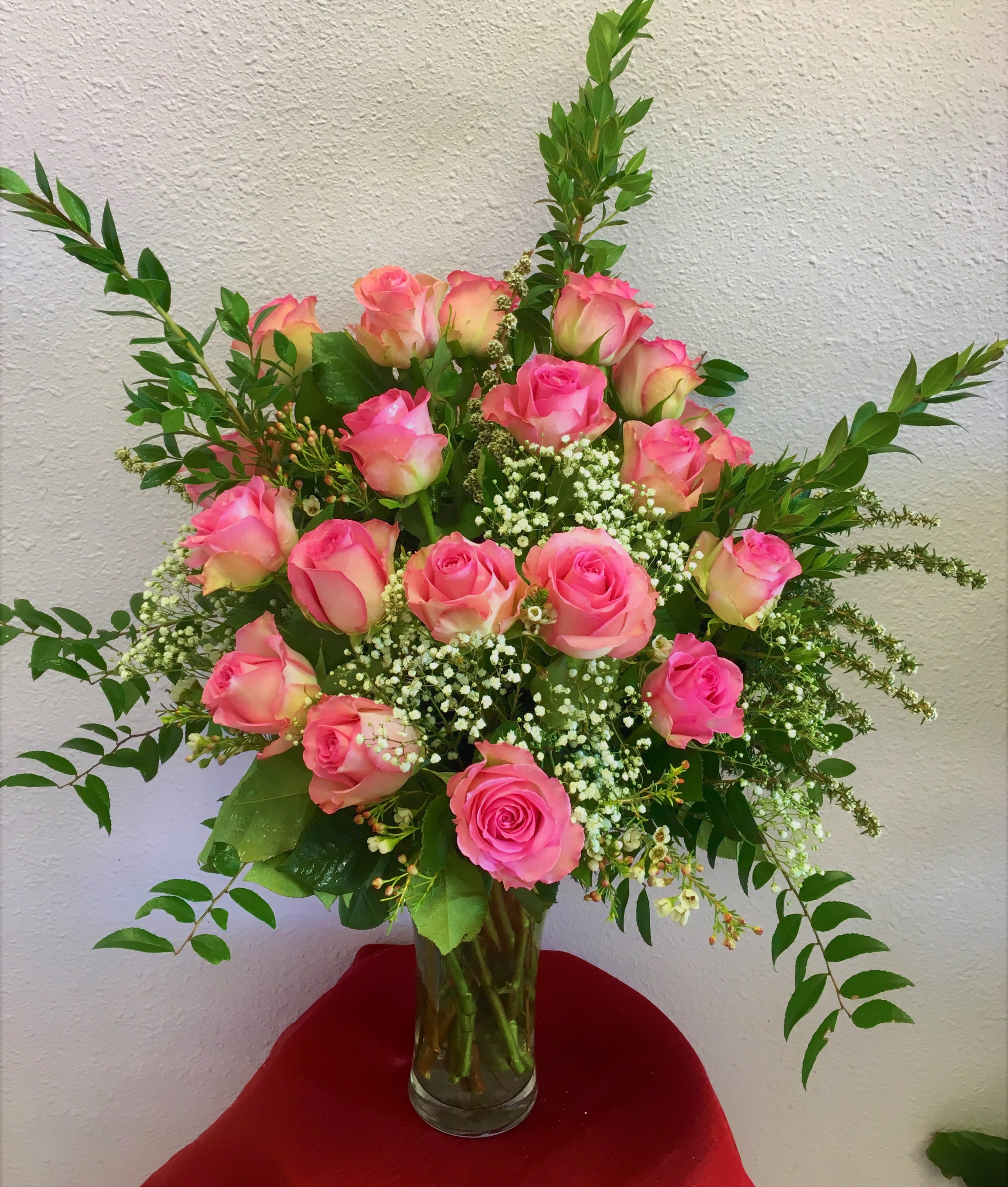Pink roses arranged in a clear glass vase with white filler flowers