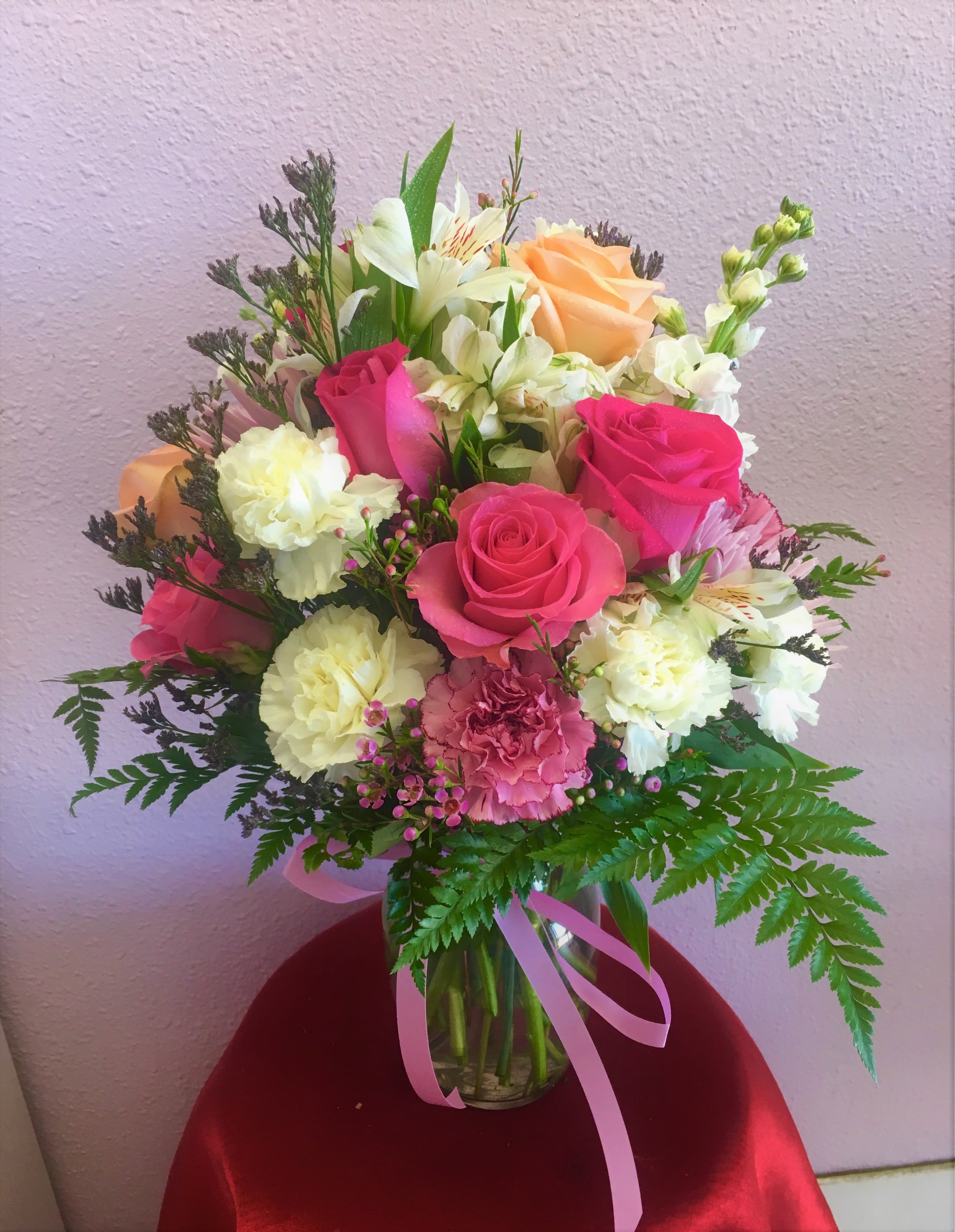 Bouquet of pink and peach roses with white flowers in a glass vase