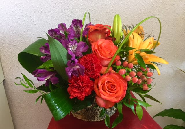 Beautiful Tropics By Forever Flowers - Orange Roses, yellow Lilies, Carnations, purple Alstro's, with an assortment of greens.