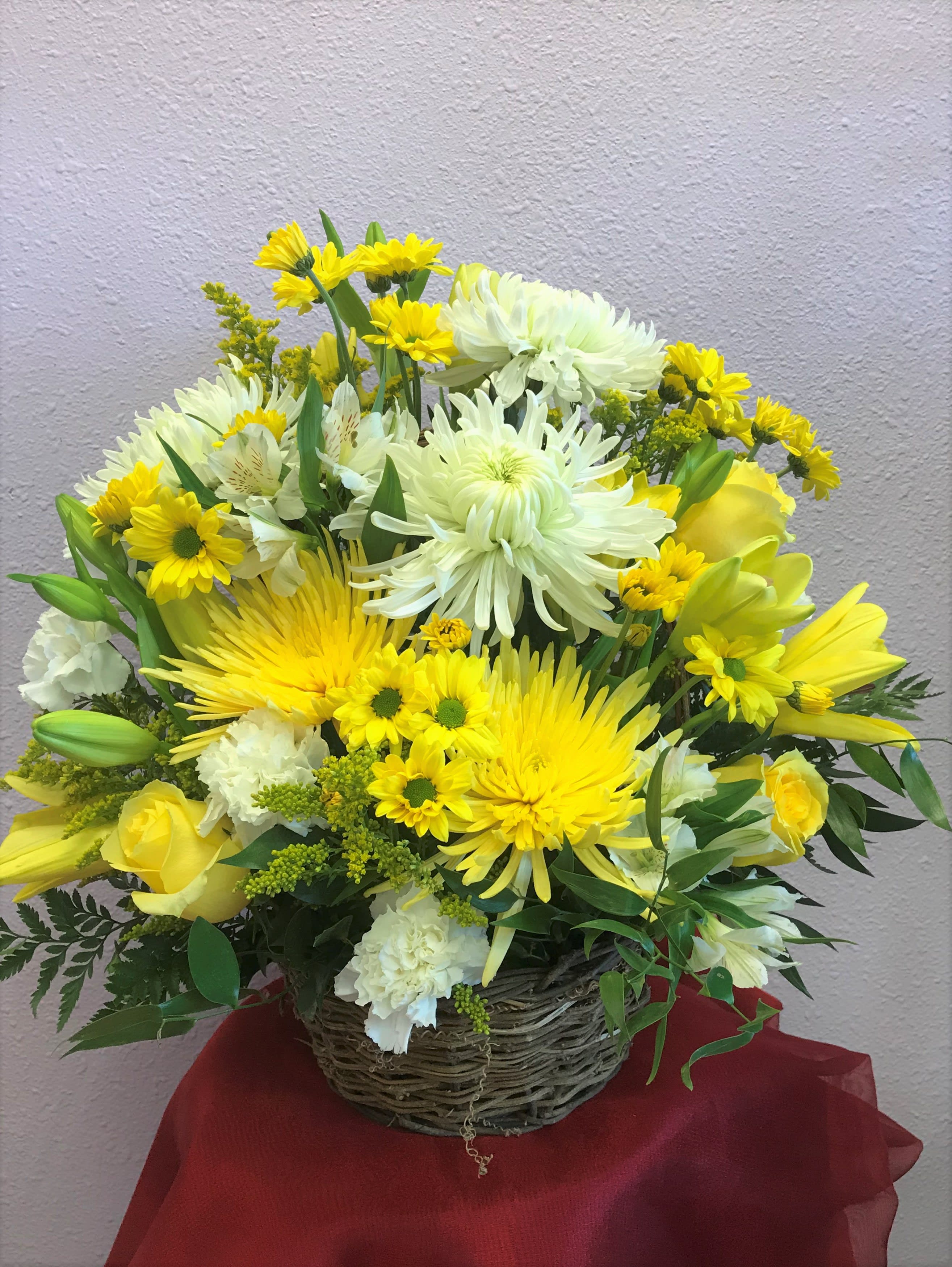 Yellow and white mixed flower arrangement in a wicker basket
