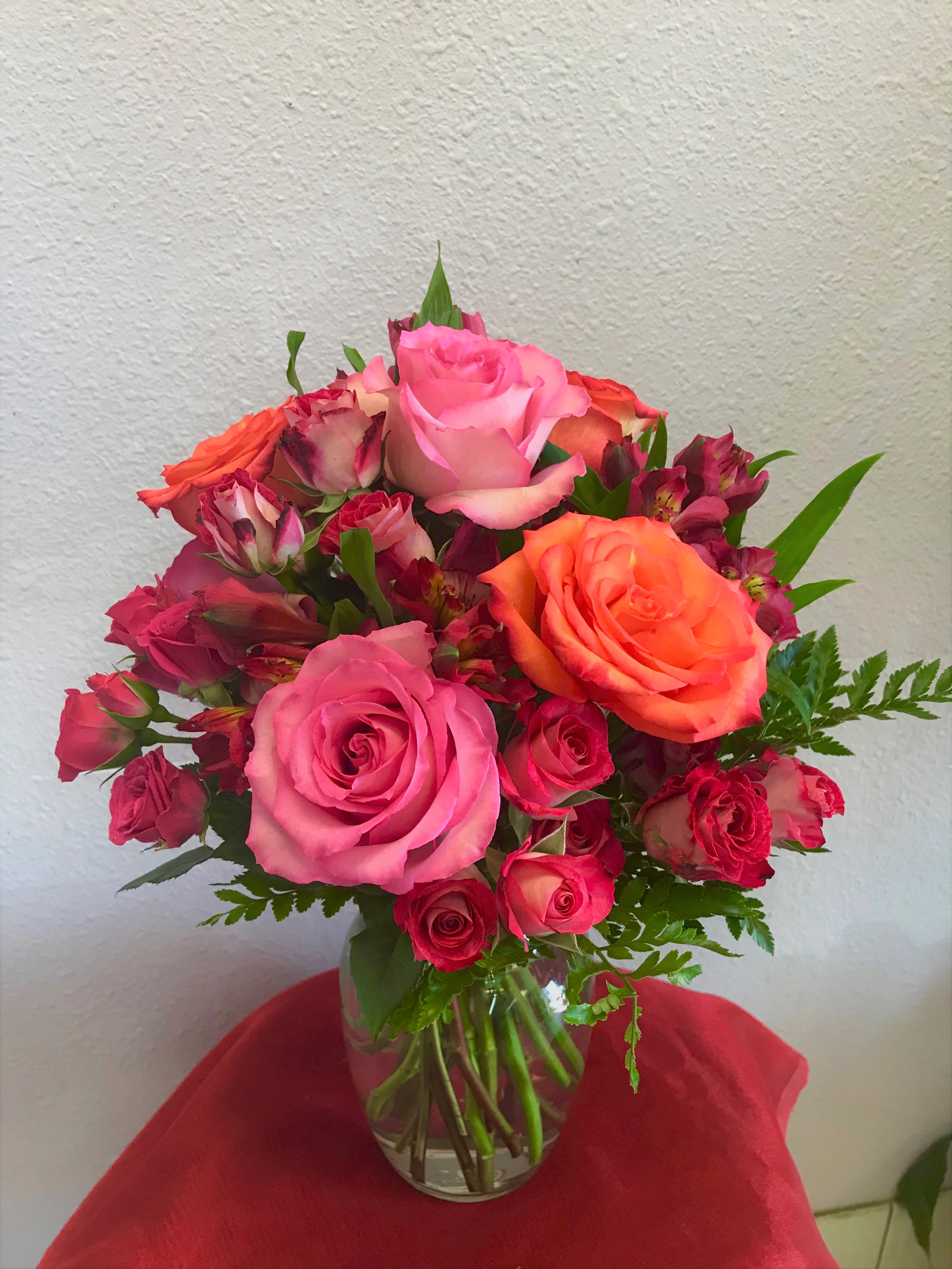 Pink and orange roses arranged in a clear glass vase