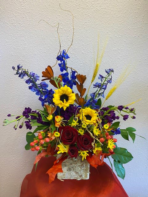 The Colors Of Fall by Forever Flowers - Sunflowers, Red Roses, Blue Delphinium, Huckleberries, Stock, in a birch wood box with dry wheat.  