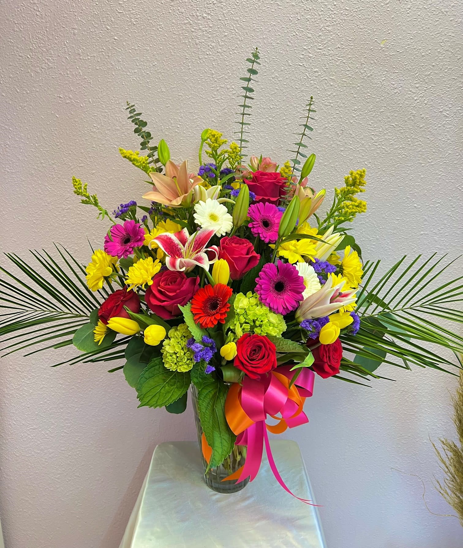 Colorful mixed bouquet in a clear glass vase with ribbon