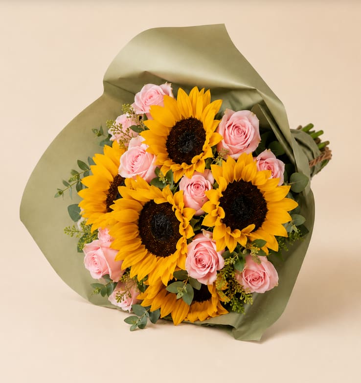 Bouquet of yellow sunflowers and pink roses wrapped in green paper