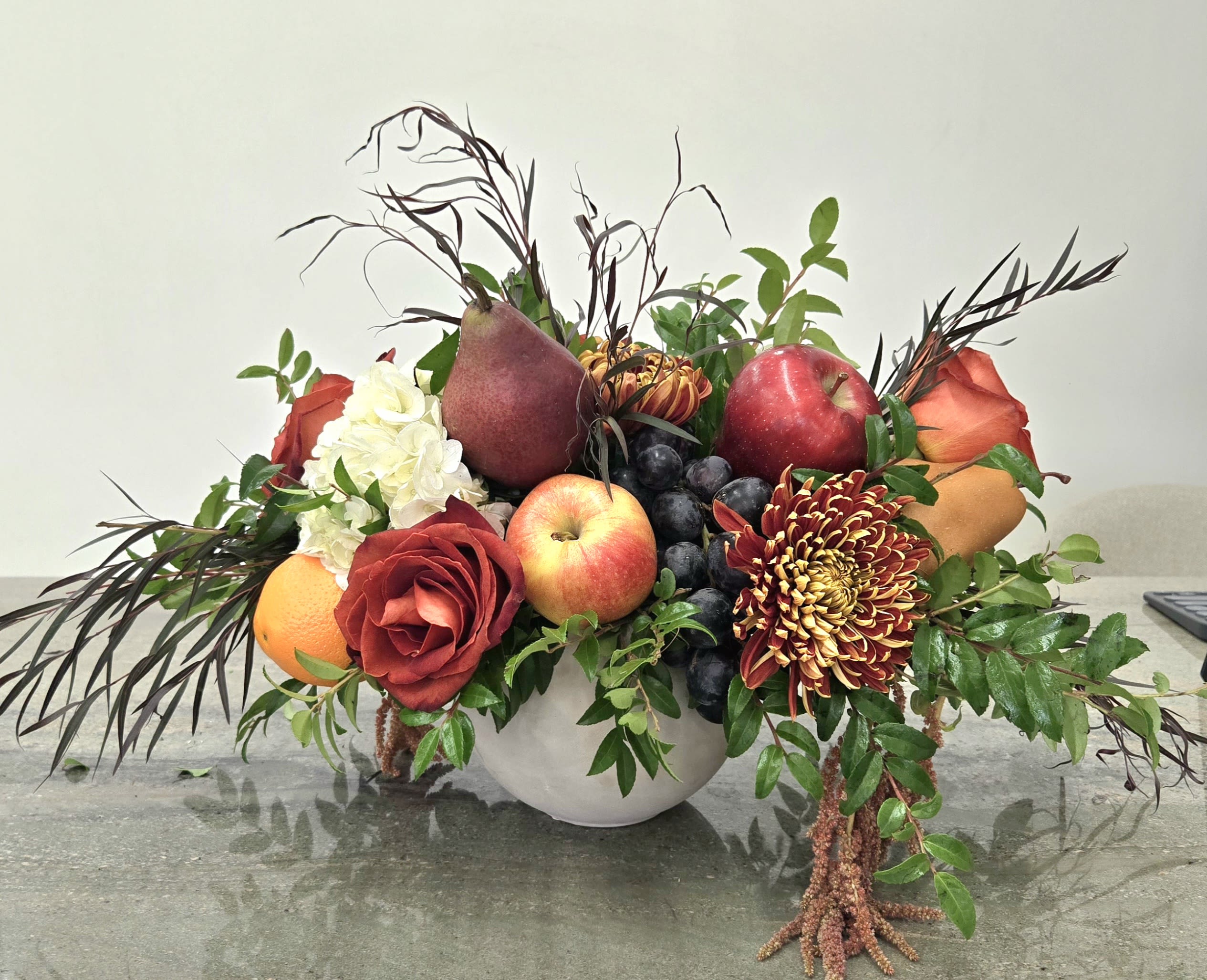 Fruit arrangement with roses, chrysanthemums, and a white bowl vase