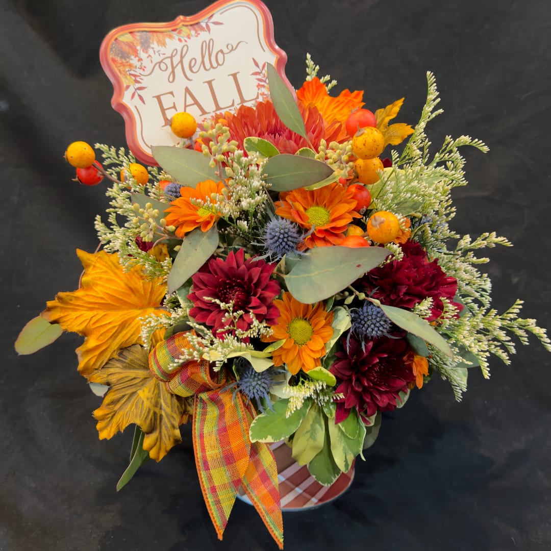 Fall bouquet with orange and burgundy flowers in a container, topped with a "Hello Fall" sign