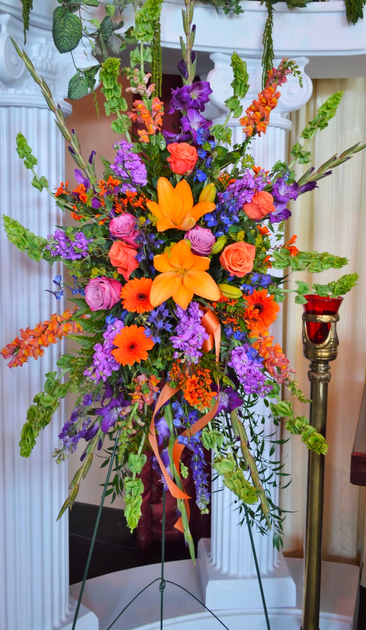 Tall floral standing arrangement with orange, purple, and pink blooms