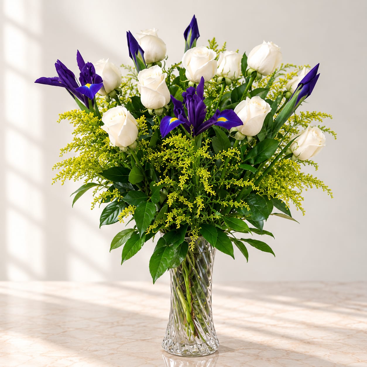 White roses and purple irises in a clear glass vase
